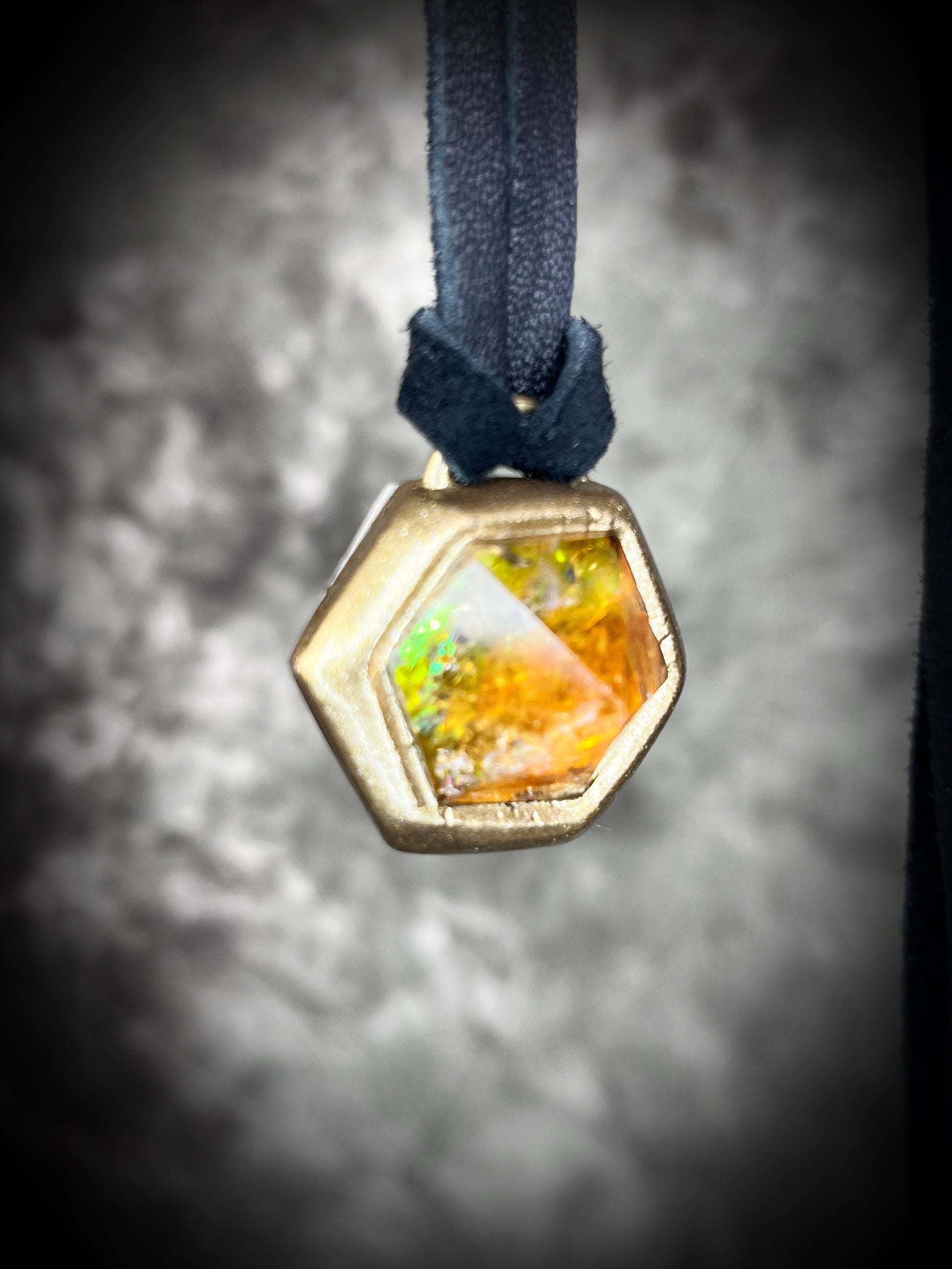 Fiery citrine hexagon crystal pendant with red, green, and orange opalescent flash in gold finish on black leather cord — handcrafted statement talisman