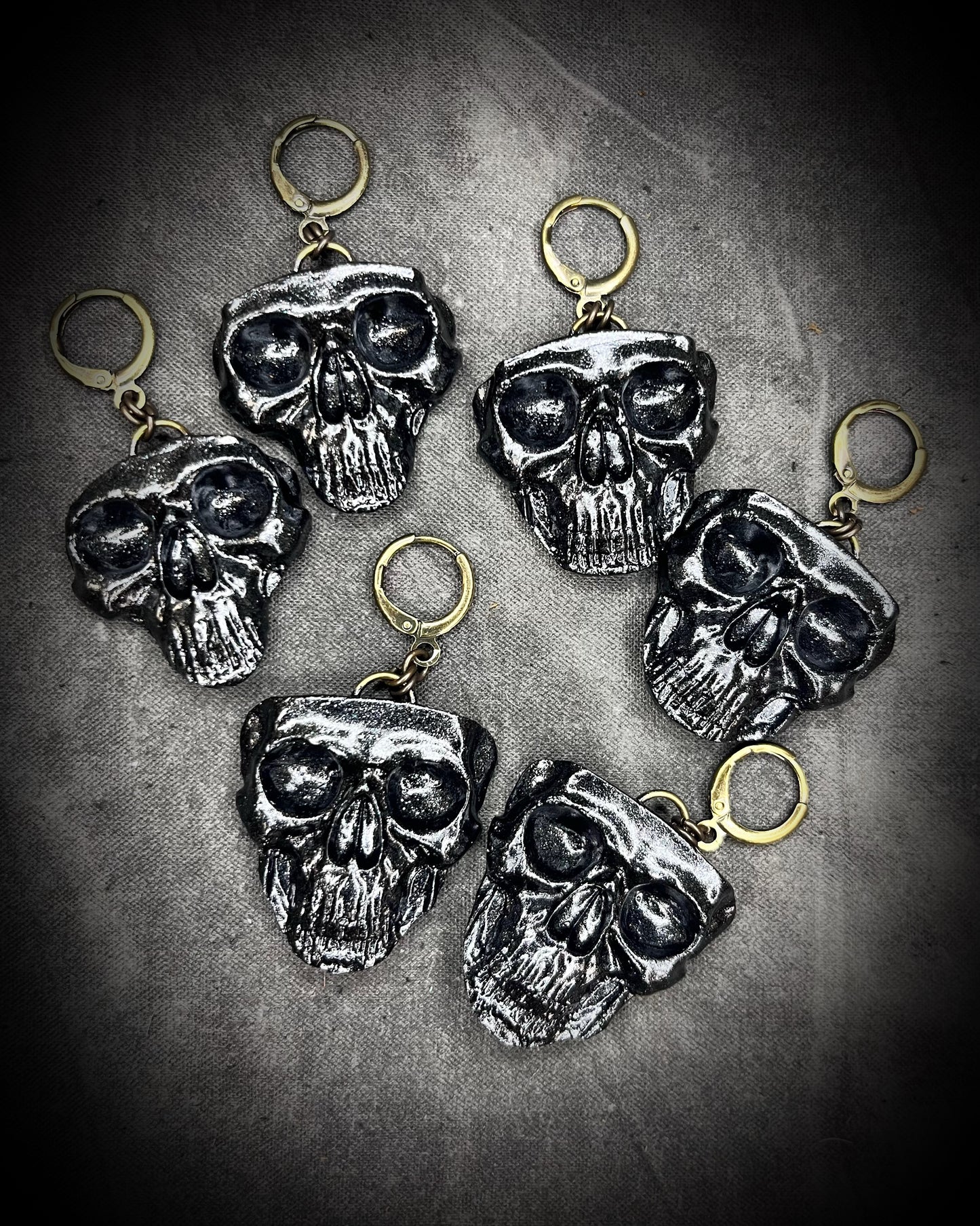 Flat lay of black skull earrings with brass hooks — handmade gothic earrings with sculptural detail.