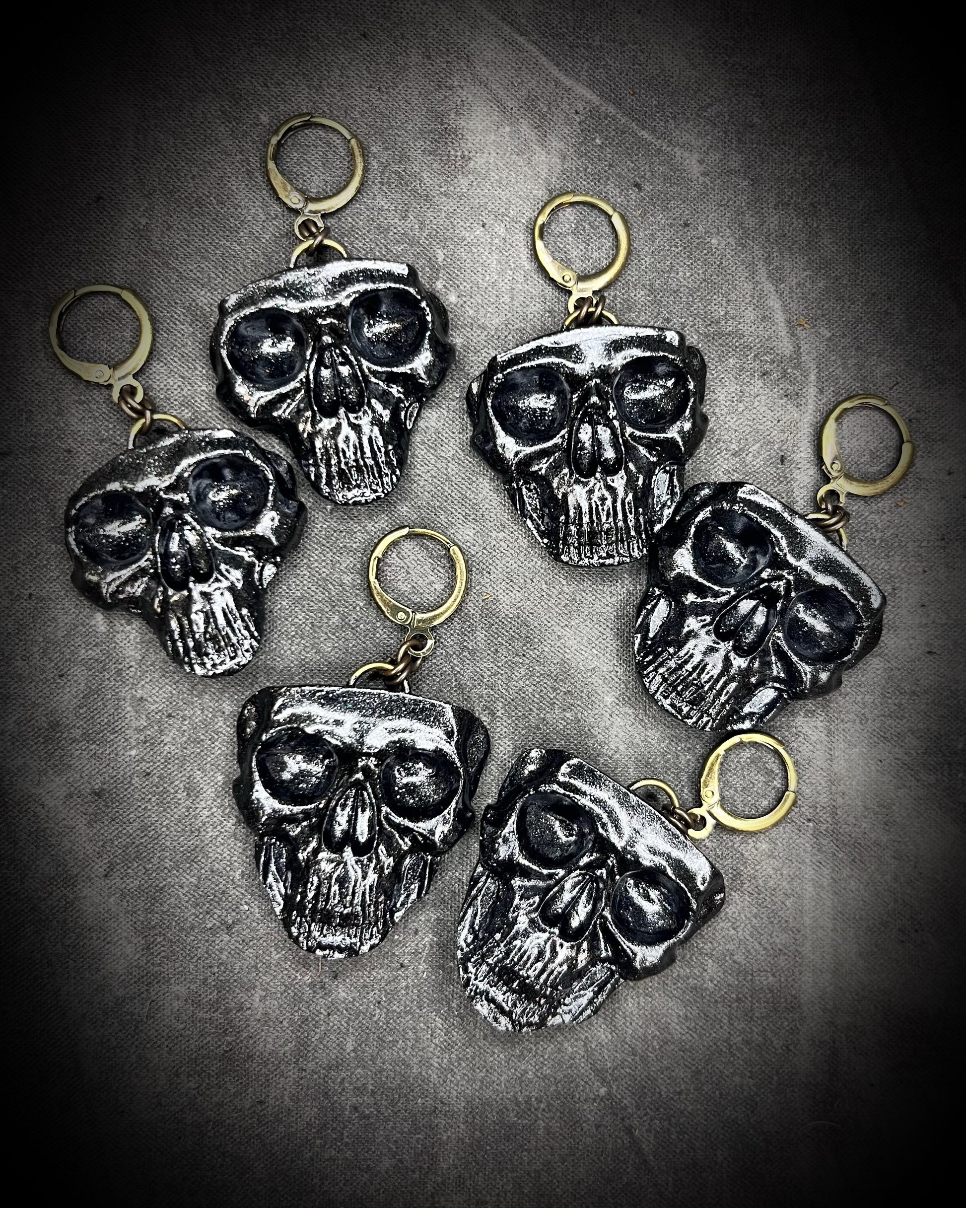 Flat lay of black skull earrings with brass hooks — handmade gothic earrings with sculptural detail.