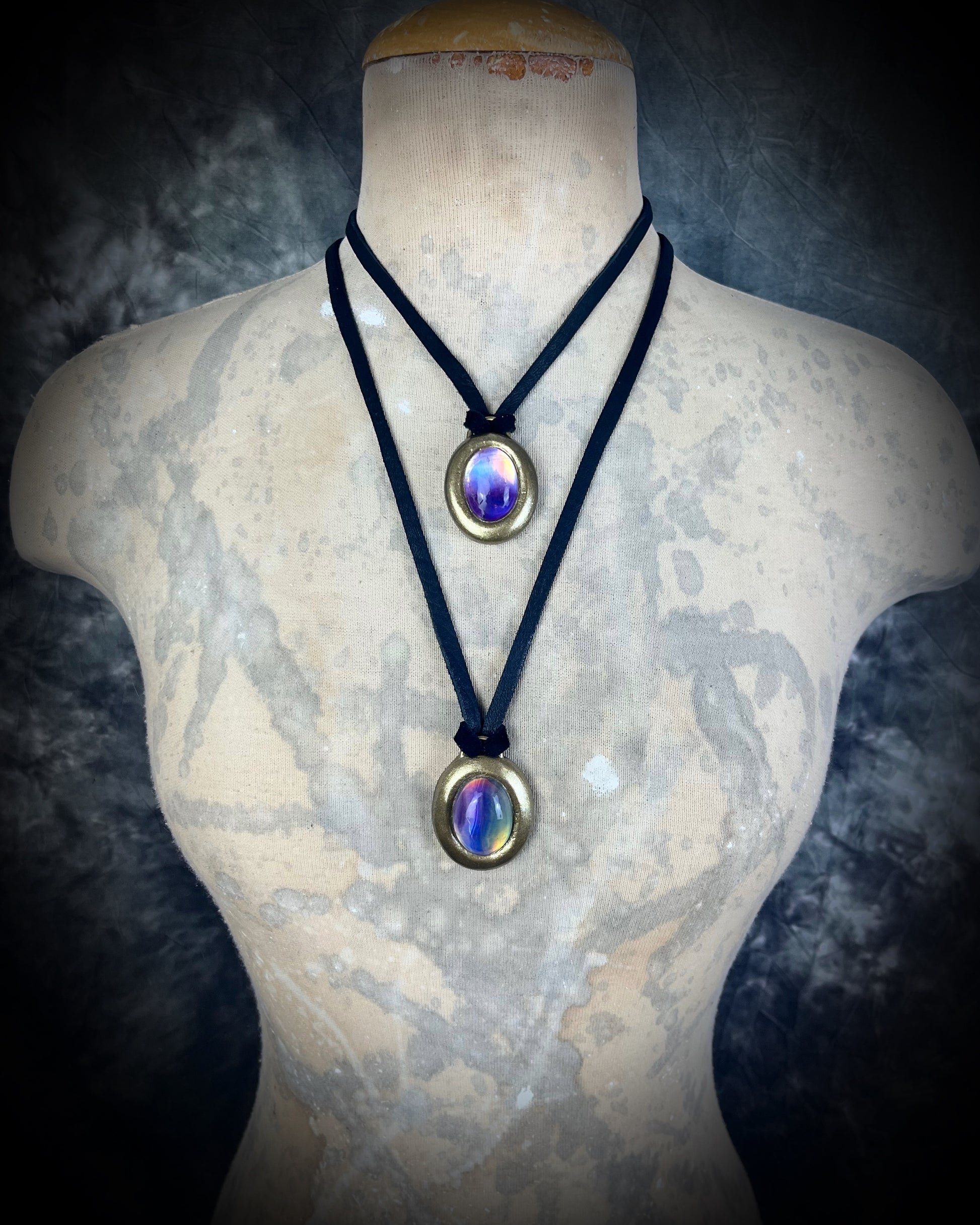 Fluorite cabochon oval necklaces in gold tone settings on black leather worn as layering necklaces on a bust– mystical crystal jewelry for clarity, focus, and balance. Handmade gemstone pendant talismans, grounding and protective fluorite statement necklaces, perfect spiritual jewelry for daily wear, meditation, or gifting.