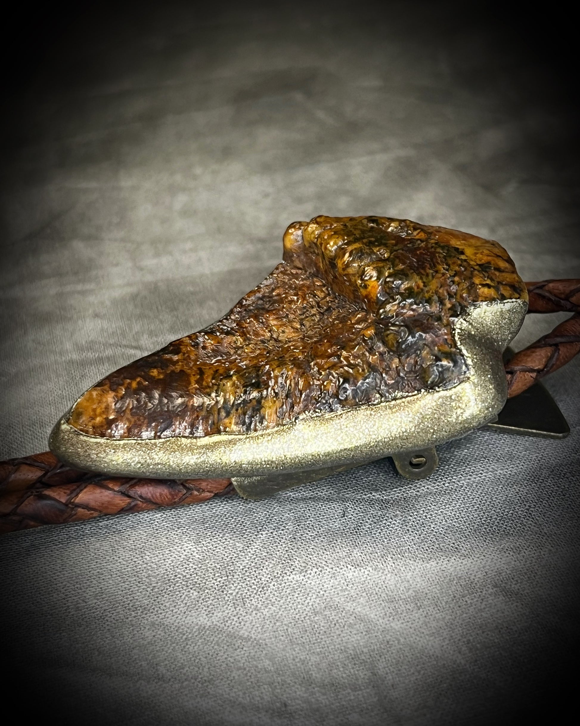 Fossilized mastodon tooth enamel bolo tie showing the natural molar crown edge, with brown leather, gold finish and gold spike tips.