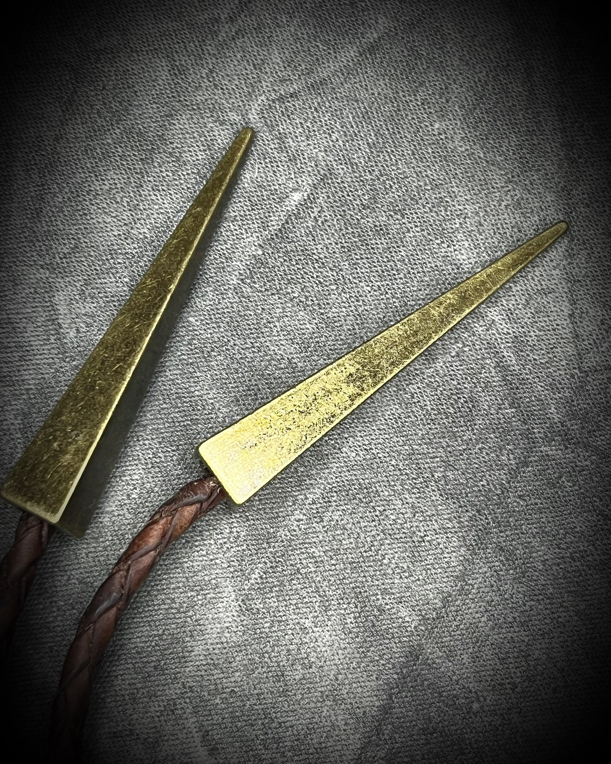 Fossilized mastodon tooth enamel bolo tie showing the natural molar crown edge, with brown leather, gold finish and gold spike tips.