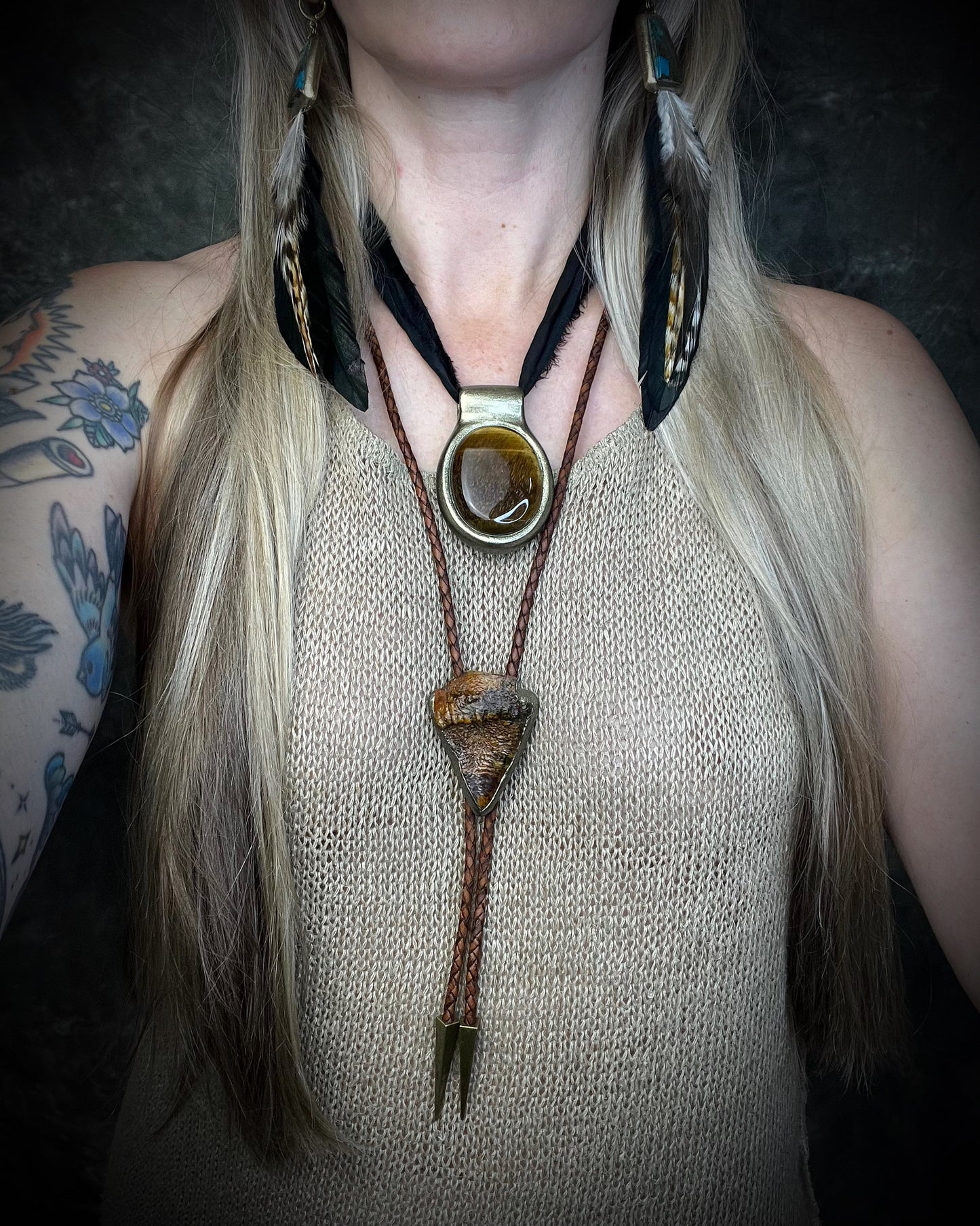 Fossilized mastodon tooth enamel bolo tie showing the natural molar crown edge, with brown leather, gold finish and gold spike tips.