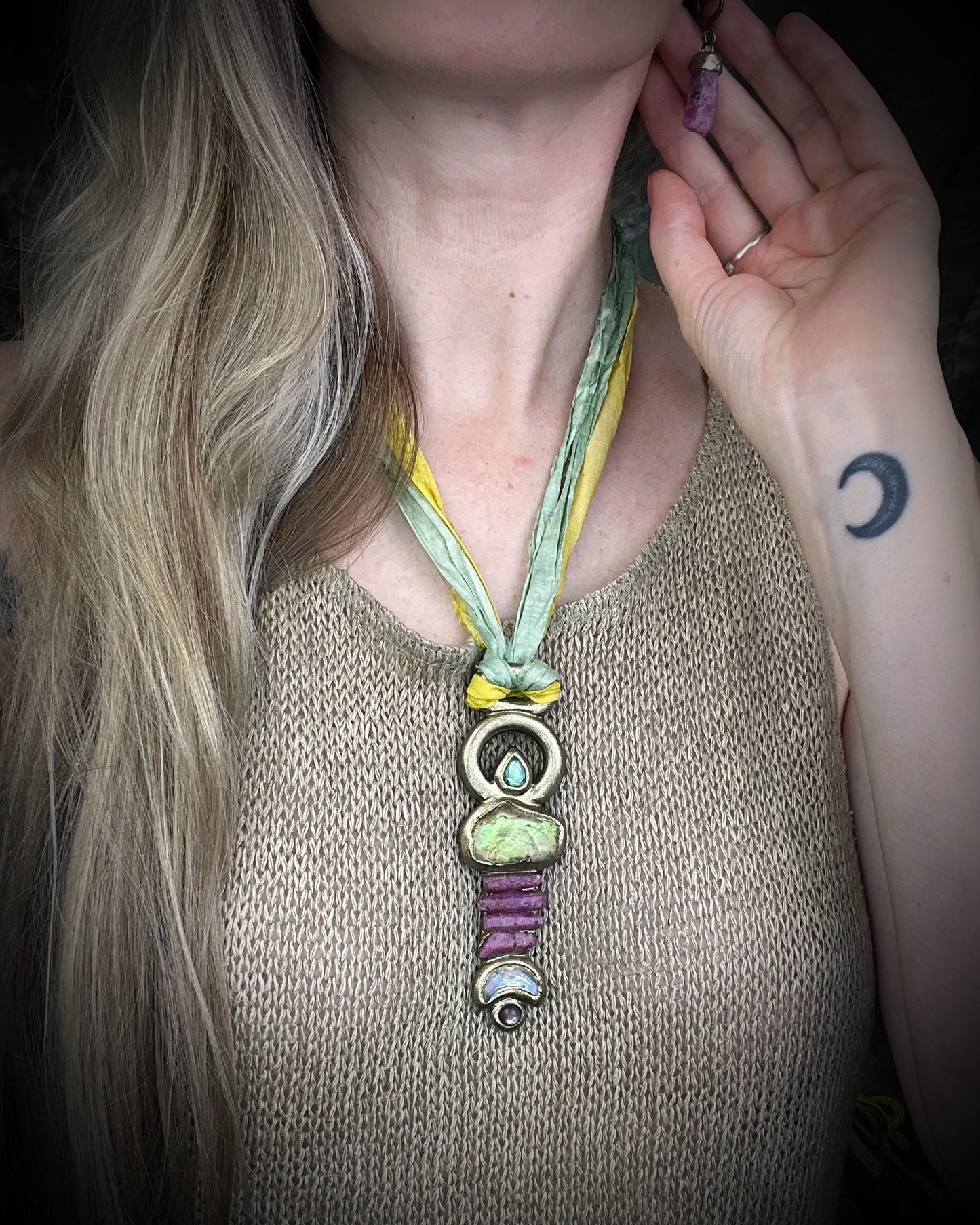 Fully hand sculpted Libyan Desert Glass talisman pendant with raw ruby crystals, prasiolite moon, lepidolite, green tourmaline, and luminous shifting color on recycled silk. Museum grade art jewelry by Become Spellbound.