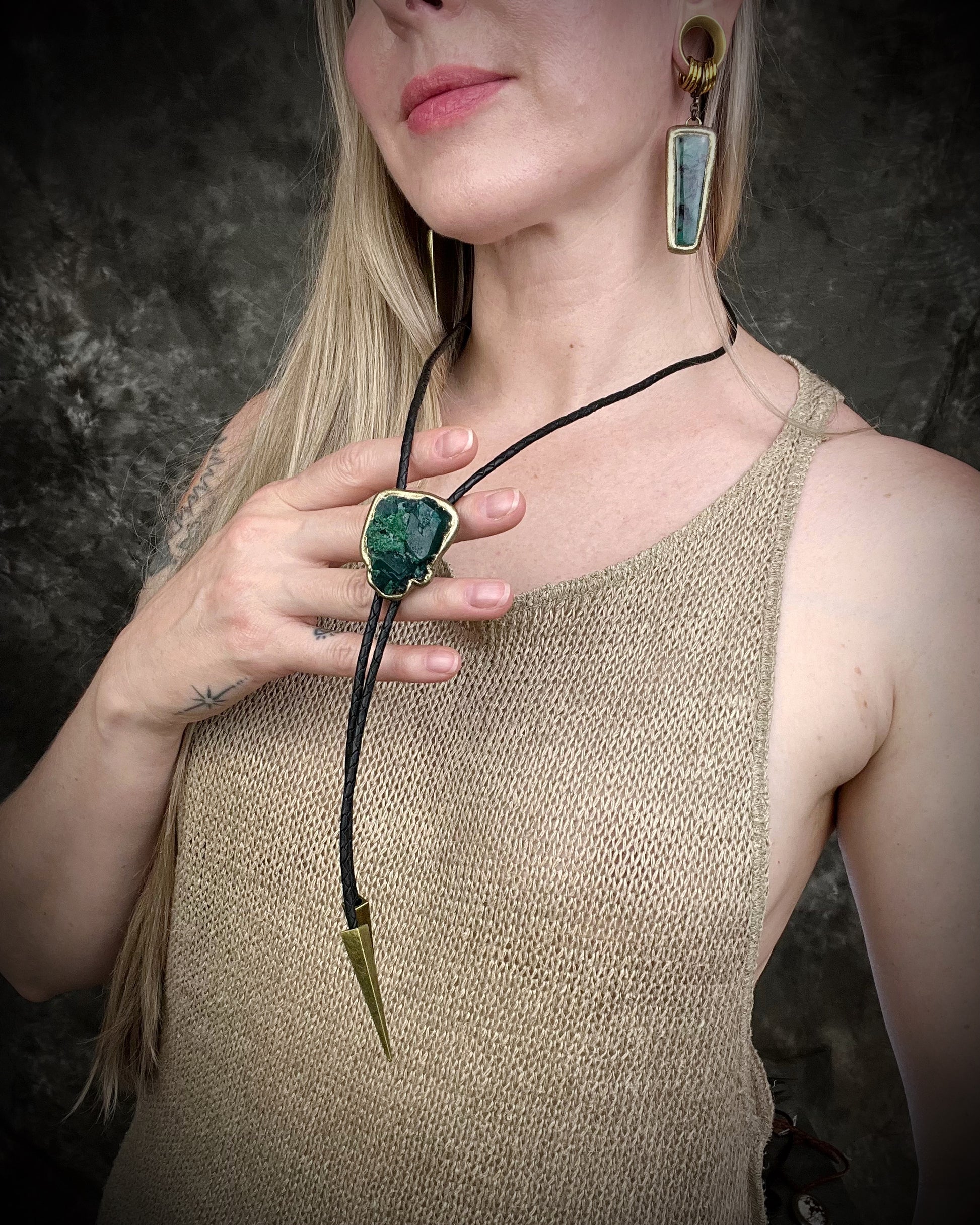 Gemmy Dioptase crystal bolo tie in deep green hues framed in a gold finish and strung on black bolo tie leather with gold tone brass spike tips. Gemstone bolo tie western inspired jewelry for him. Handmade in Baltimore, Maryland.