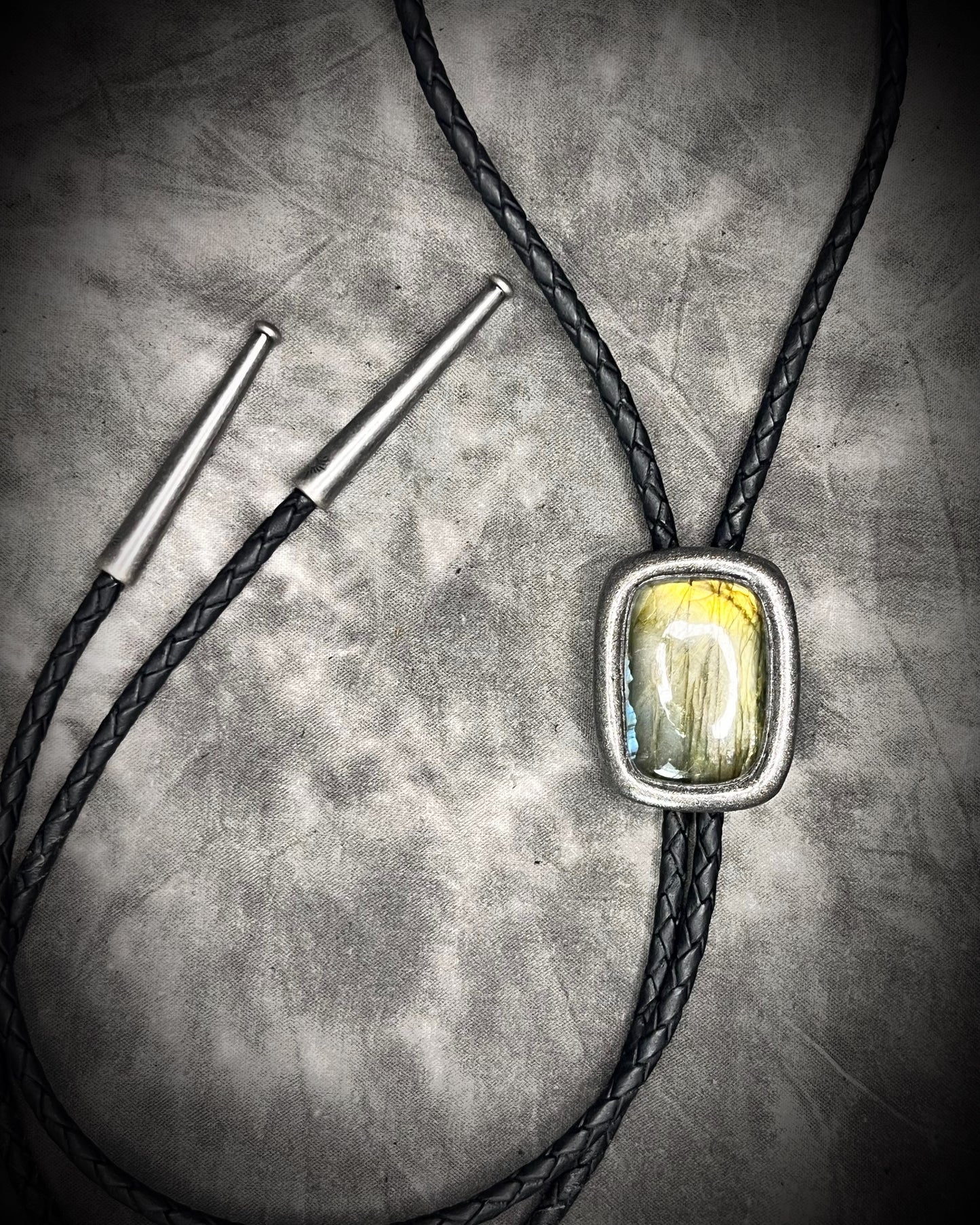 Bolo tie with a stone pendant on a textured surface