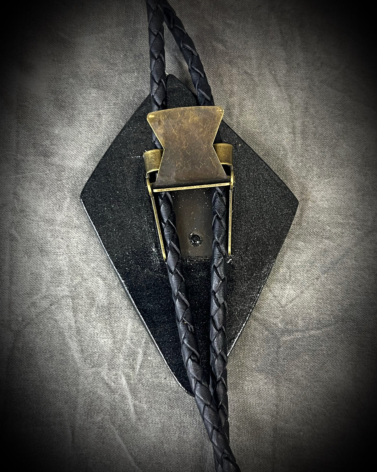 Genuine asymmetrical kite-shaped psilomelane bolo tie with black finish, black leather cord, and black spike bolo tips. Handmade by Become Spellbound.