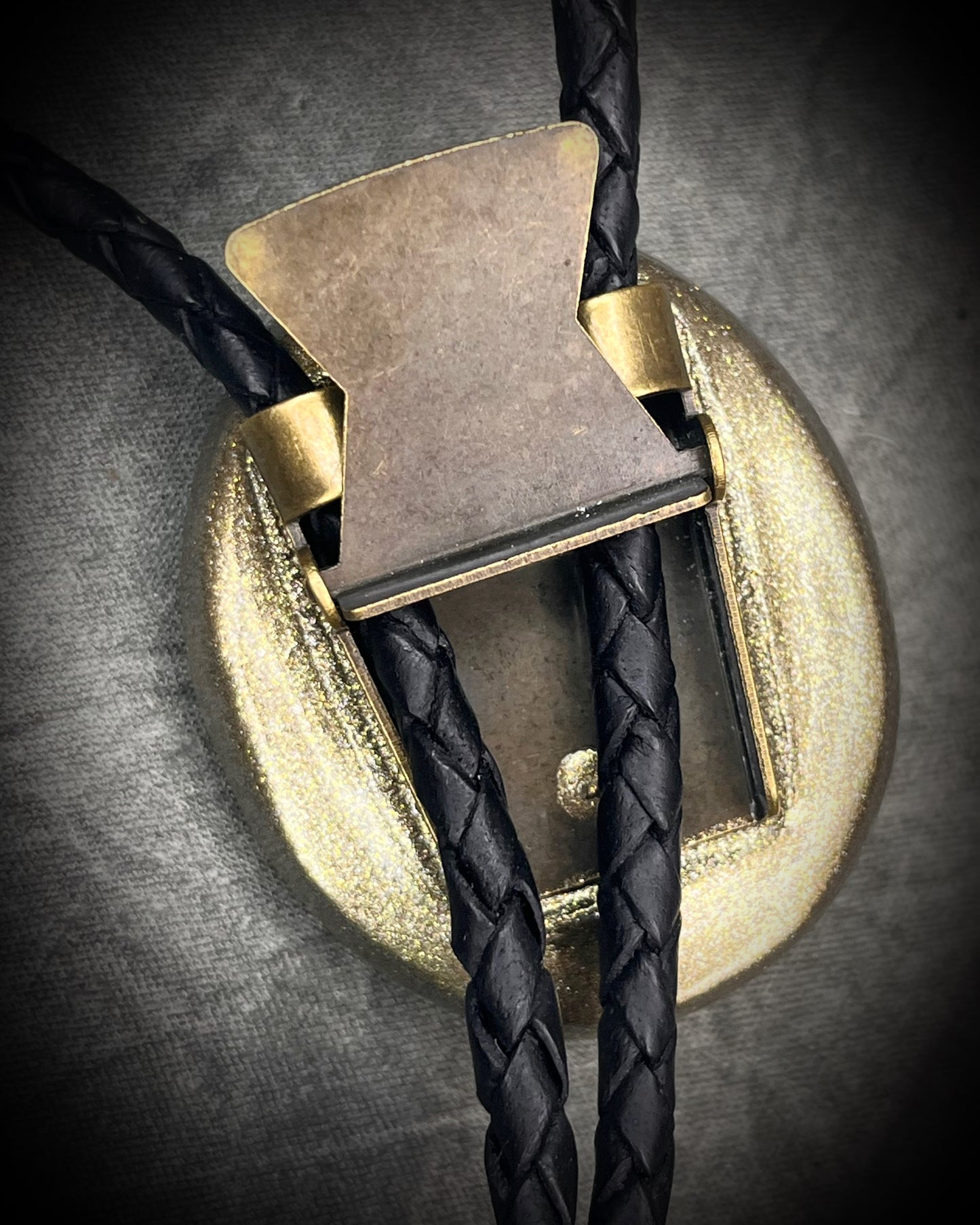 Glowing mystical orange labradorite bolo tie with blue stripe in a gold setting, black leather cord, and antique gold bolo tips. Handmade by Become Spellbound.