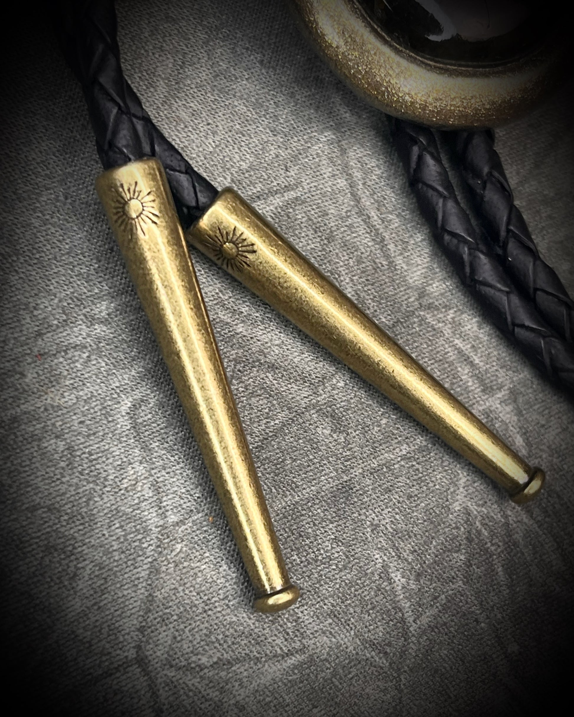 Glowing mystical orange labradorite bolo tie with blue stripe in a gold setting, black leather cord, and antique gold bolo tips. Handmade by Become Spellbound.