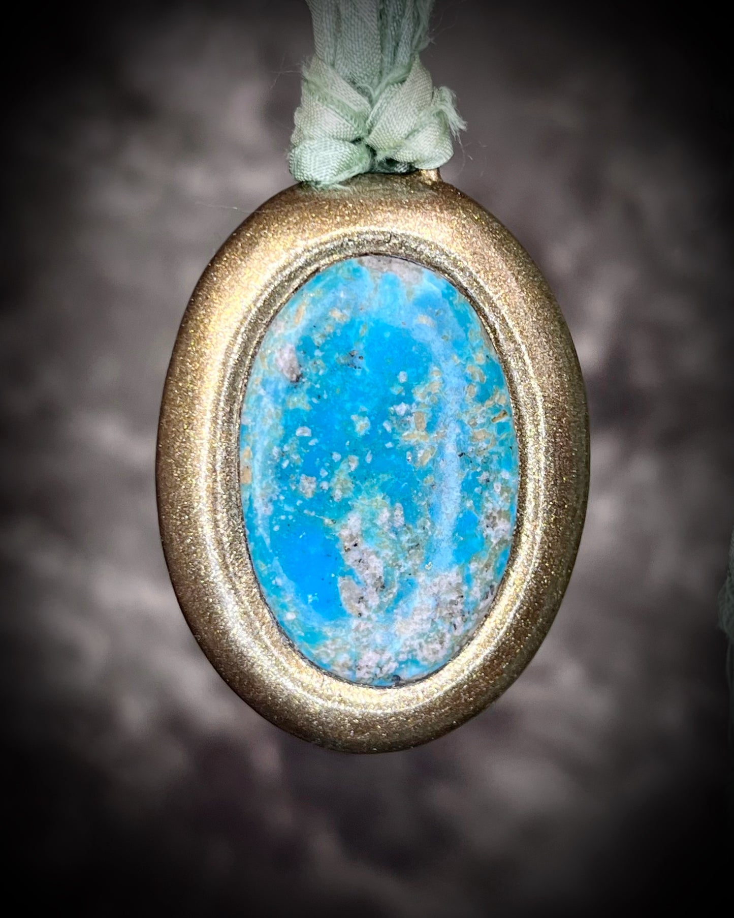 Gold-framed turquoise handmade pendant with vibrant blue green stone hung from sea green recycled silks. Oceanic treasure necklace for her. 