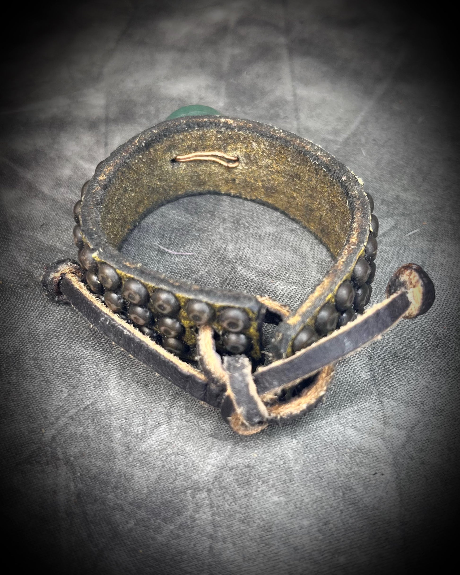 Golden brown studded leather cuff bracelet featuring a circular Green Aventurine focal stone. Rugged leatherwork with a lucky, calming stone, gift for him or her.