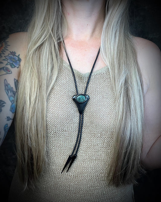 Great White shark tooth fossil bolo tie with black and turquoise-colored turquoise, black leather, black finish, and black spike tips.