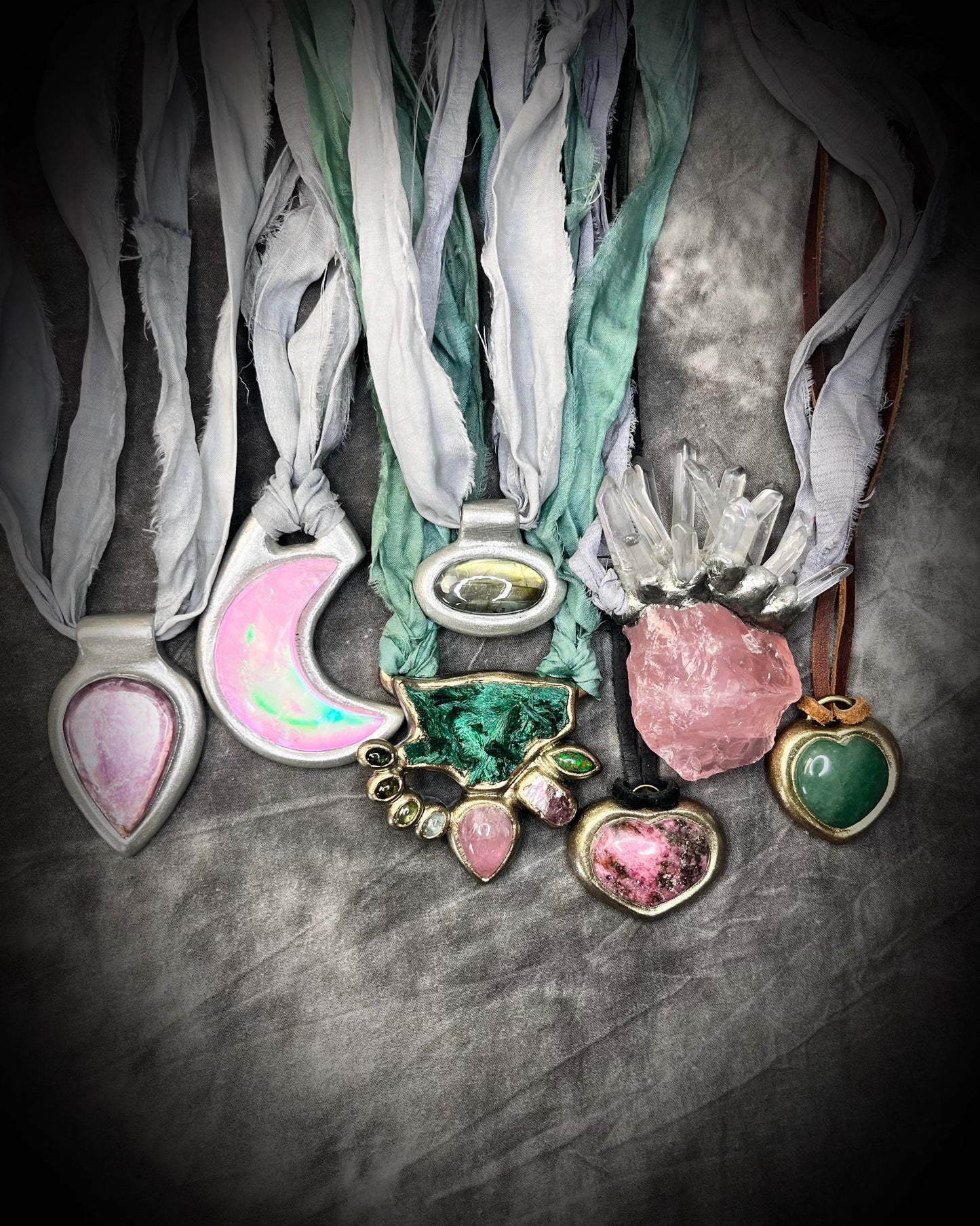 Necklaces with colorful pendants and ribbons on a textured surface