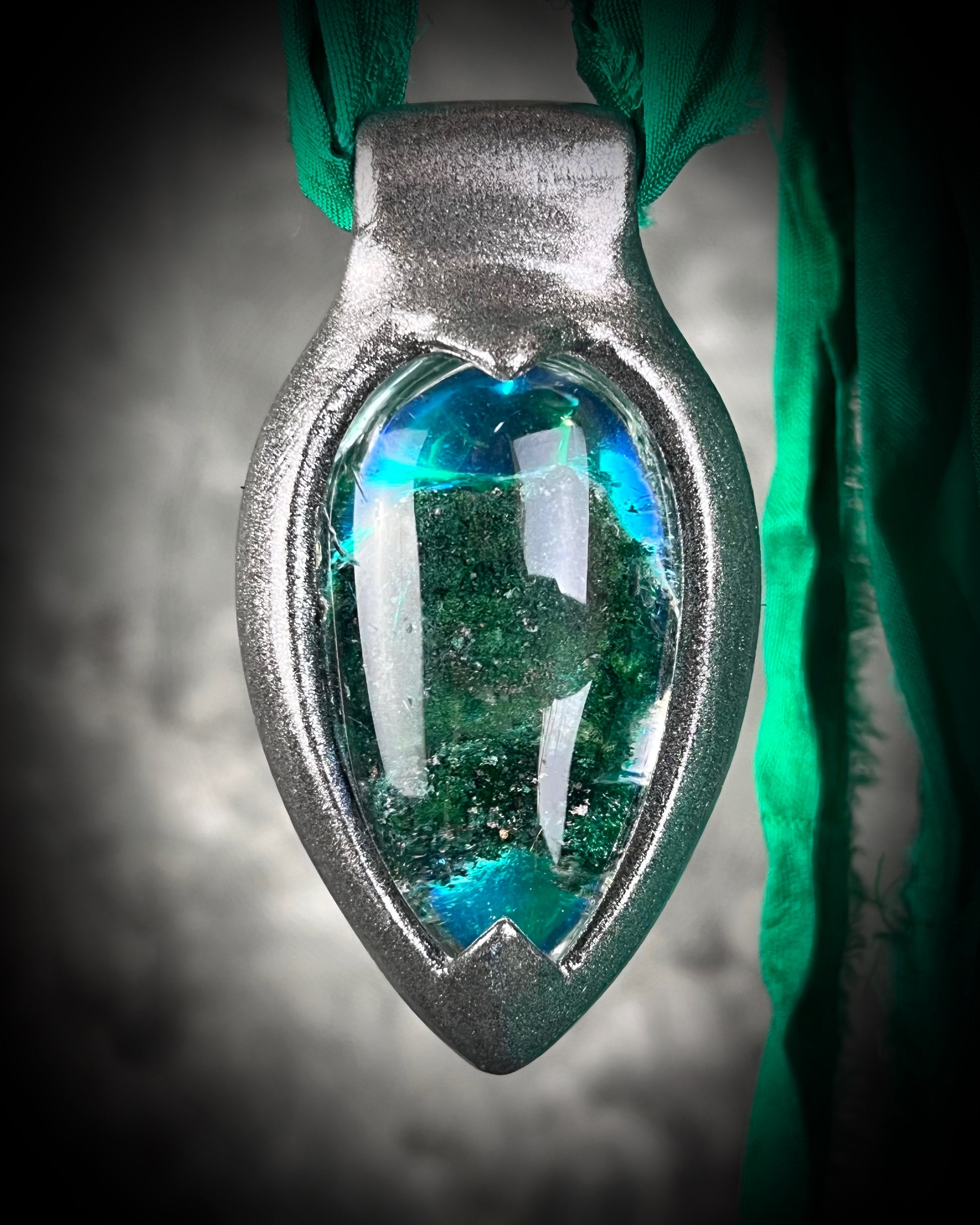 Chlorite Included Quartz necklace in a dark silver gunmetal finish on emerald green recycled silk, glowing with natural green mosslike crystal inclusions.