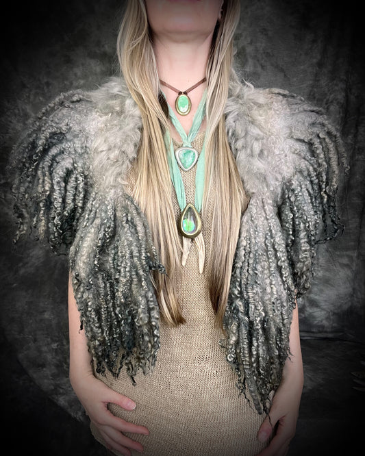 Person wearing a textured silver handmade merino wool shawl garment and multiple necklaces with heart-shaped pendants.