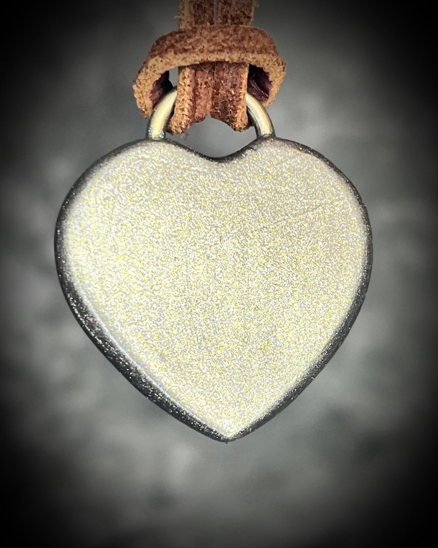 Back of Handcrafted lapis lazuli heart pendant with gold finish on brown leather cord, glowing deep blue with pyrite flecks.