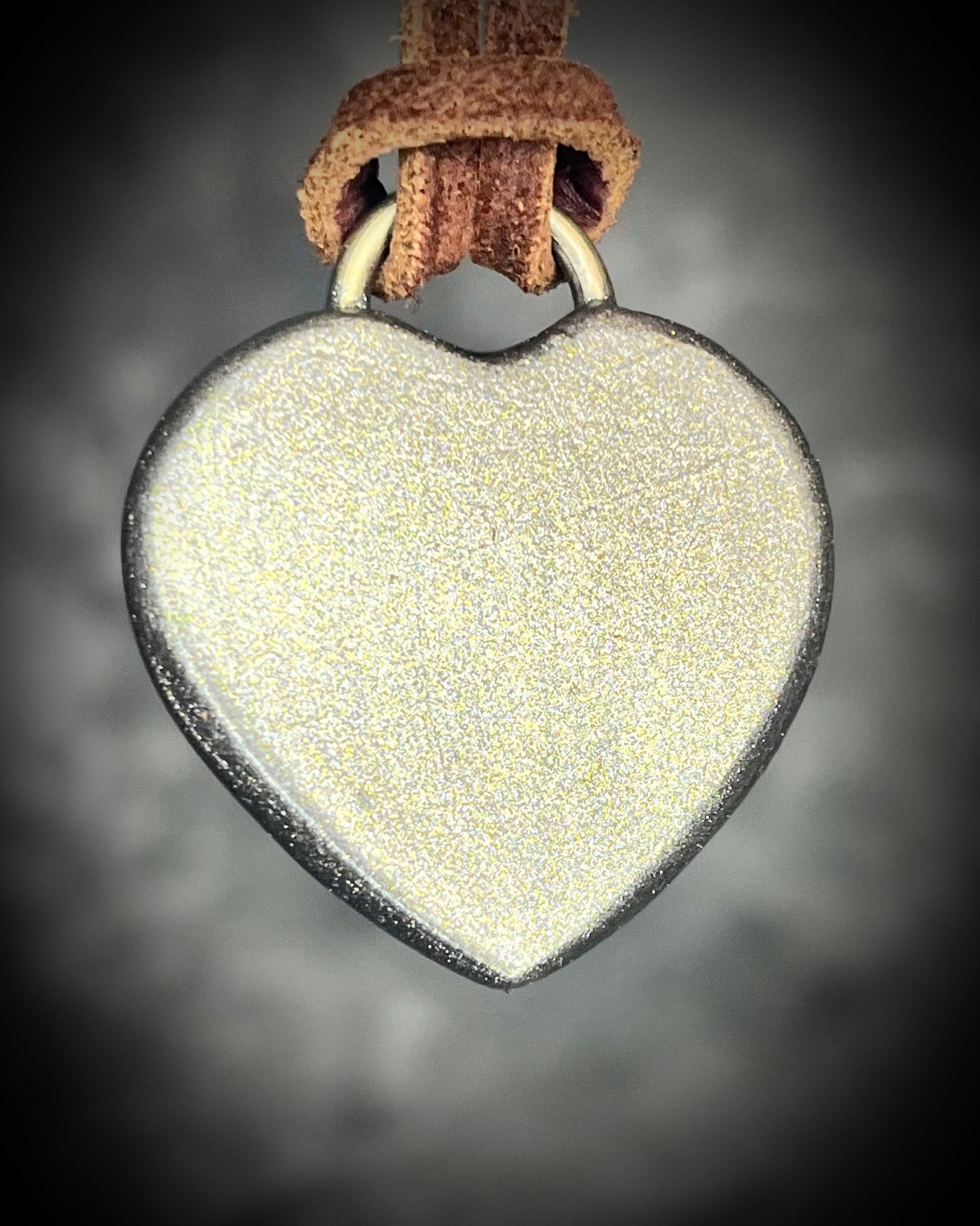 Back of Handcrafted lapis lazuli heart pendant with gold finish on brown leather cord, glowing deep blue with pyrite flecks.