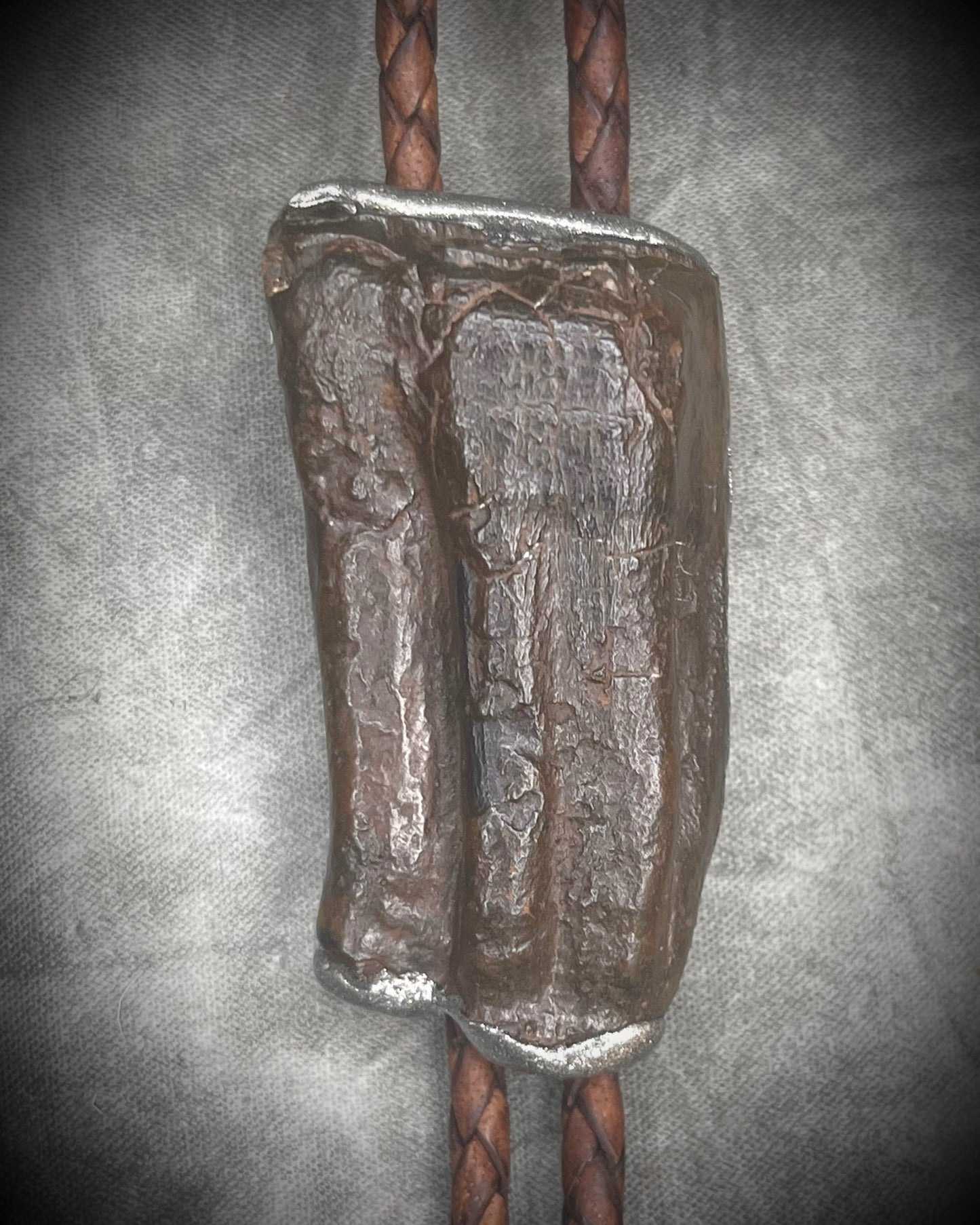Handmade Equus bolo tie featuring horse tooth fossil centerpiece with gunmetal silver sculptural detailing, brass findings, spike tip ends, and leather cord bolo necklace. Natural history talisman for him, handmade in Baltimore Maryland. 