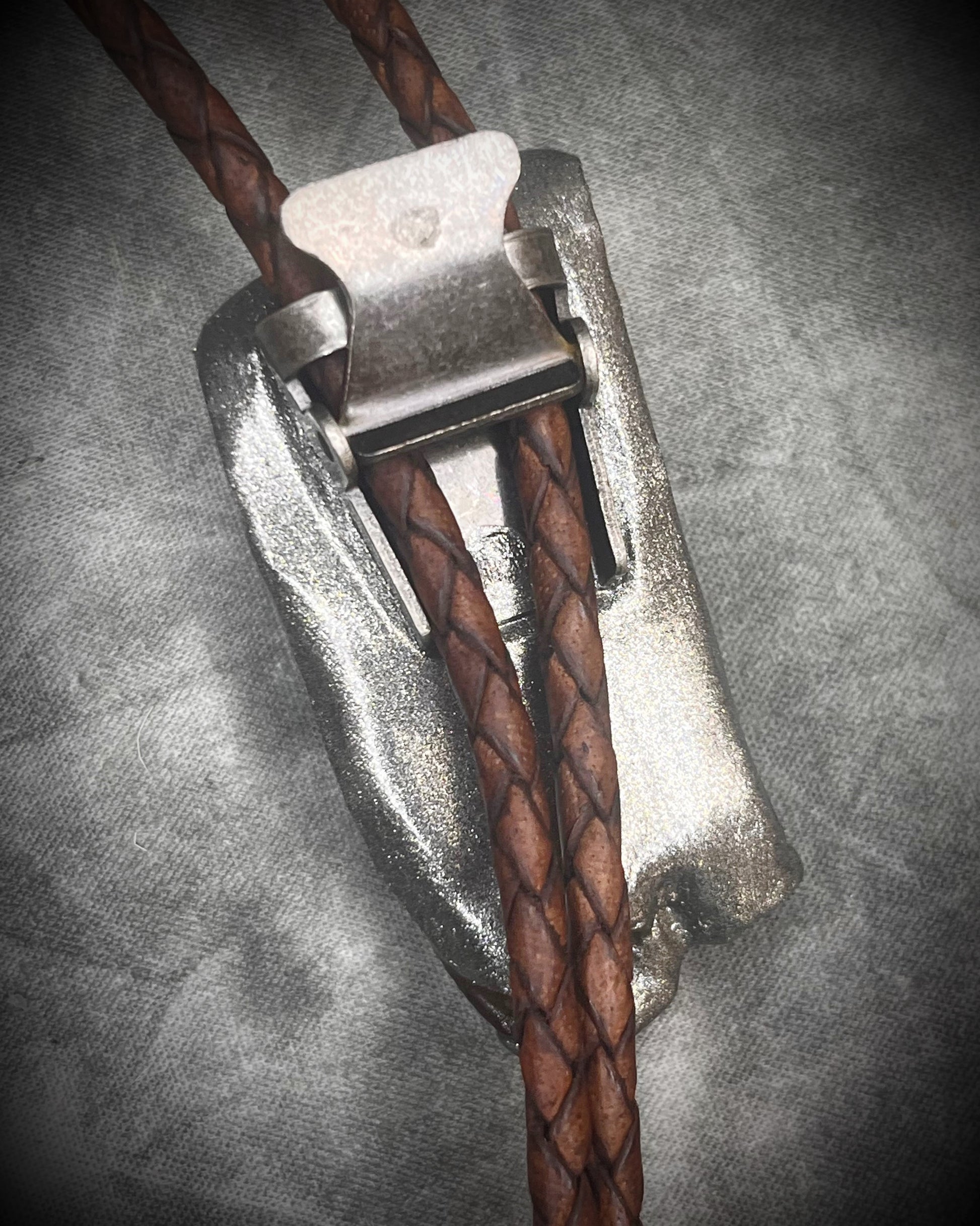 Handmade Equus bolo tie featuring horse tooth fossil centerpiece with gunmetal silver sculptural detailing, brass findings, spike tip ends, and leather cord bolo necklace. Natural history talisman for him, handmade in Baltimore Maryland. 