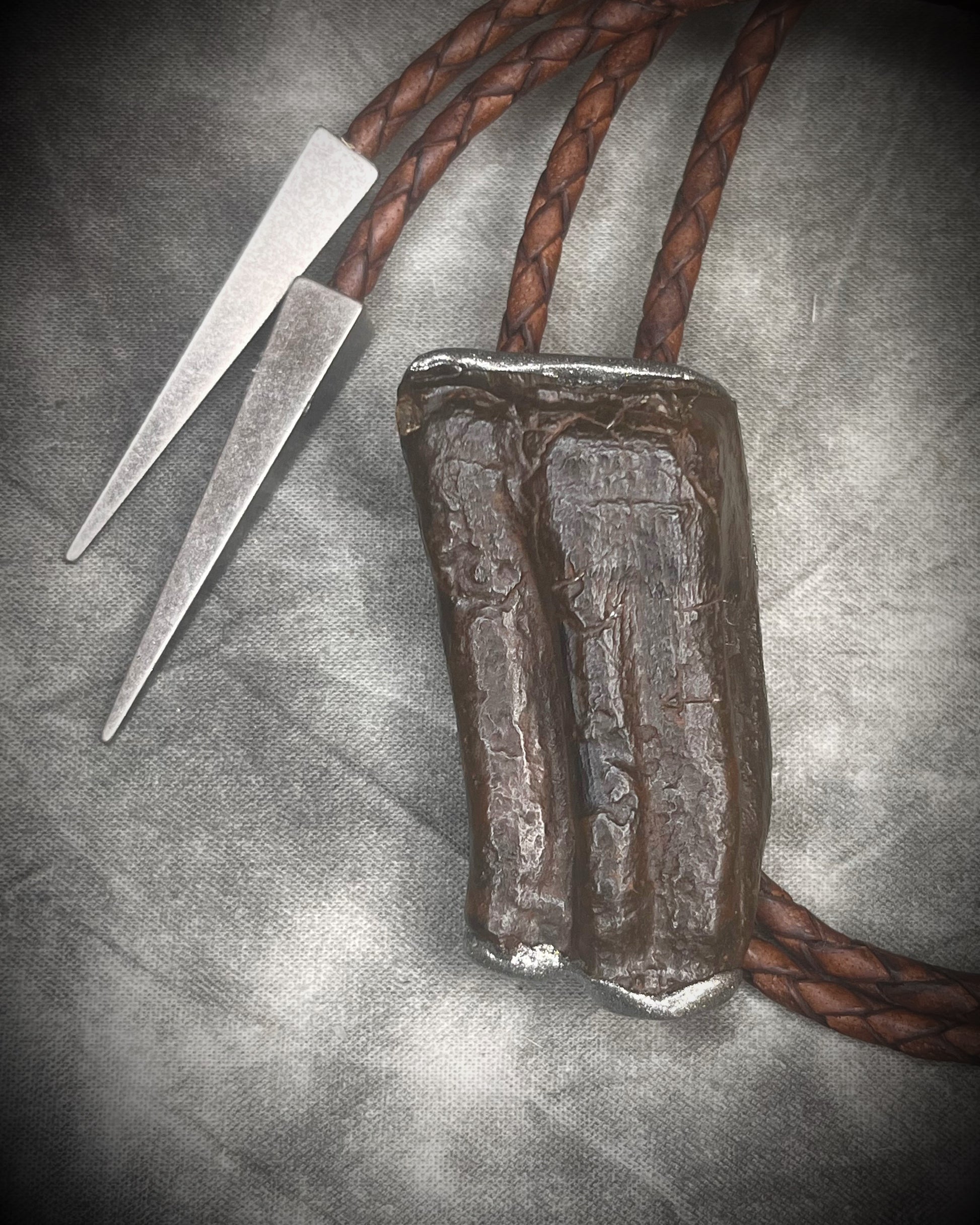 Handmade Equus bolo tie featuring horse tooth fossil centerpiece with gunmetal silver sculptural detailing, brass findings, spike tip ends, and leather cord bolo necklace. Natural history talisman for him, handmade in Baltimore Maryland. 