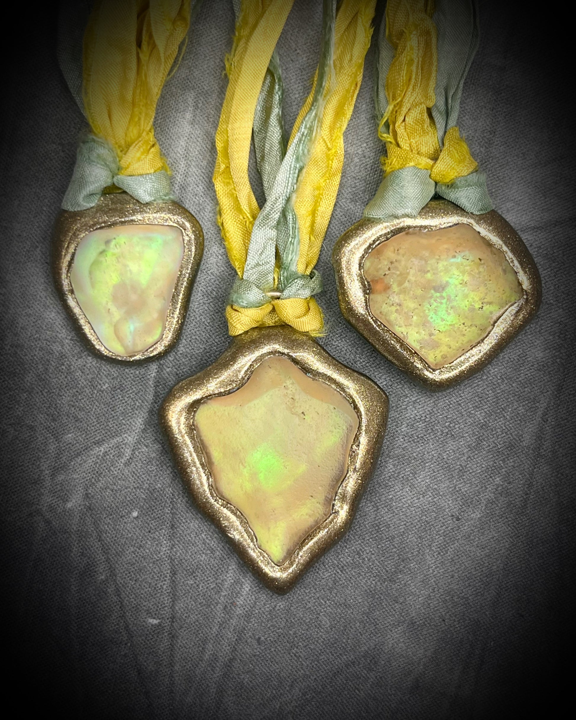 Handmade Libyan Desert Glass necklaces with luminous shifting flashes of green, gold, peach, and rose on sea green and yellow recycled silk by Become Spellbound.