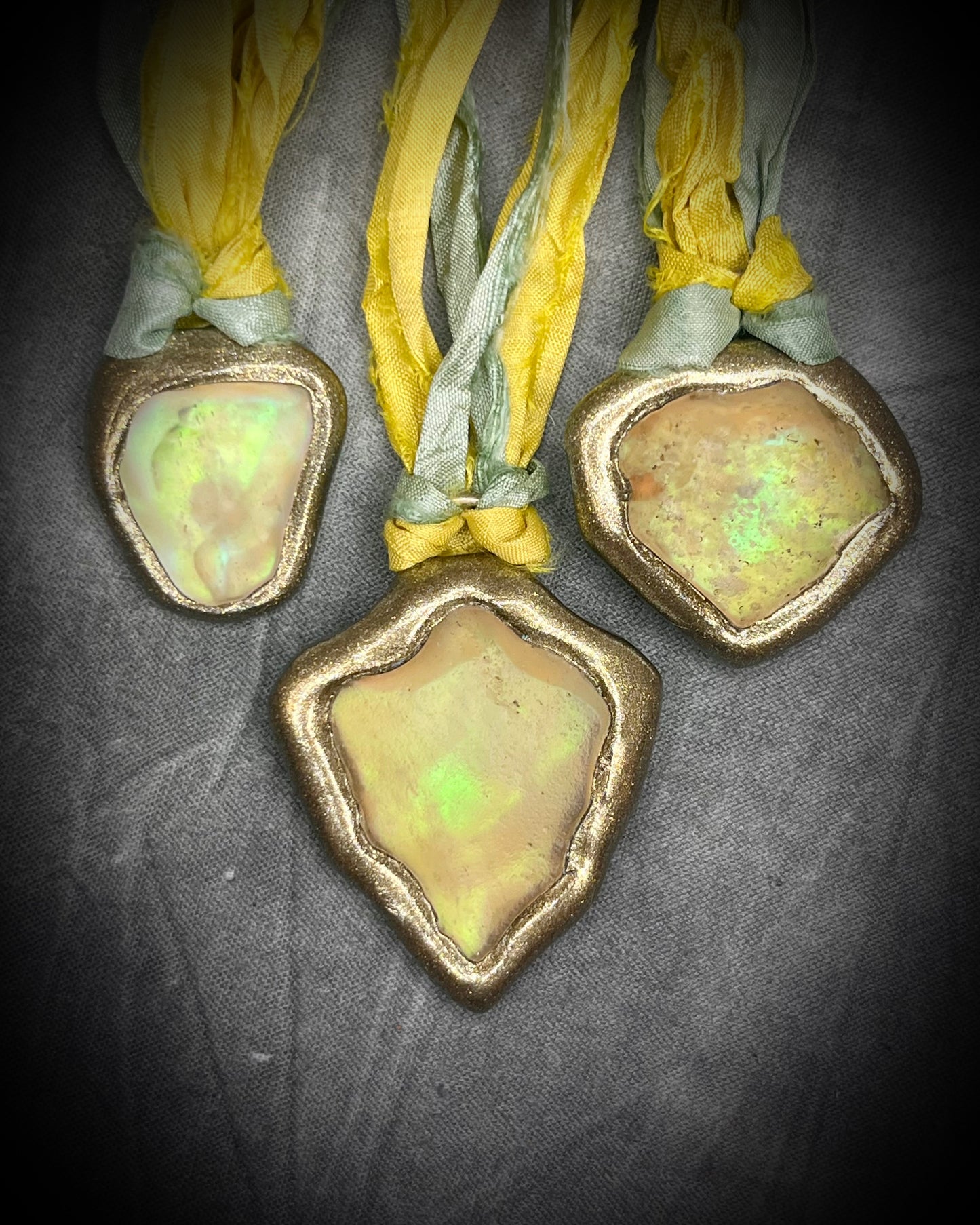 Handmade Libyan Desert Glass necklaces with luminous shifting flashes of green, gold, peach, and rose on sea green and yellow recycled silk by Become Spellbound.