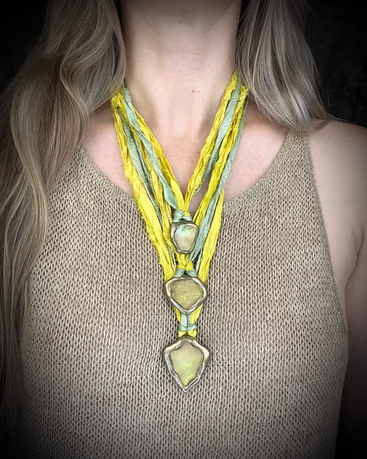 Handmade Libyan Desert Glass necklaces with luminous shifting flashes of green, gold, peach, and rose on sea green and yellow recycled silk by Become Spellbound.