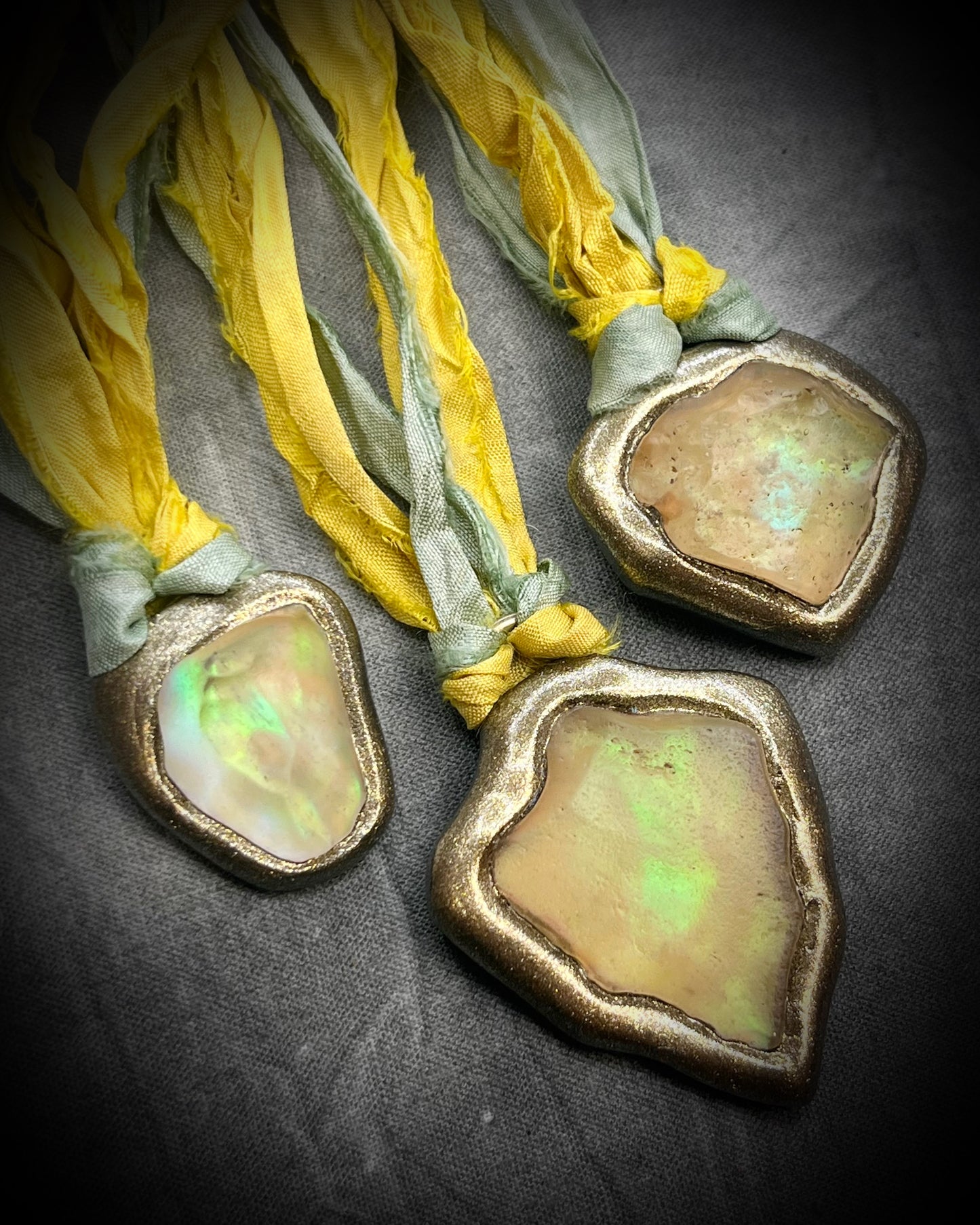 Handmade Libyan Desert Glass pendant necklaces with luminous shifting flashes of green, gold, peach, and rose on sea green and yellow recycled silk by Become Spellbound.