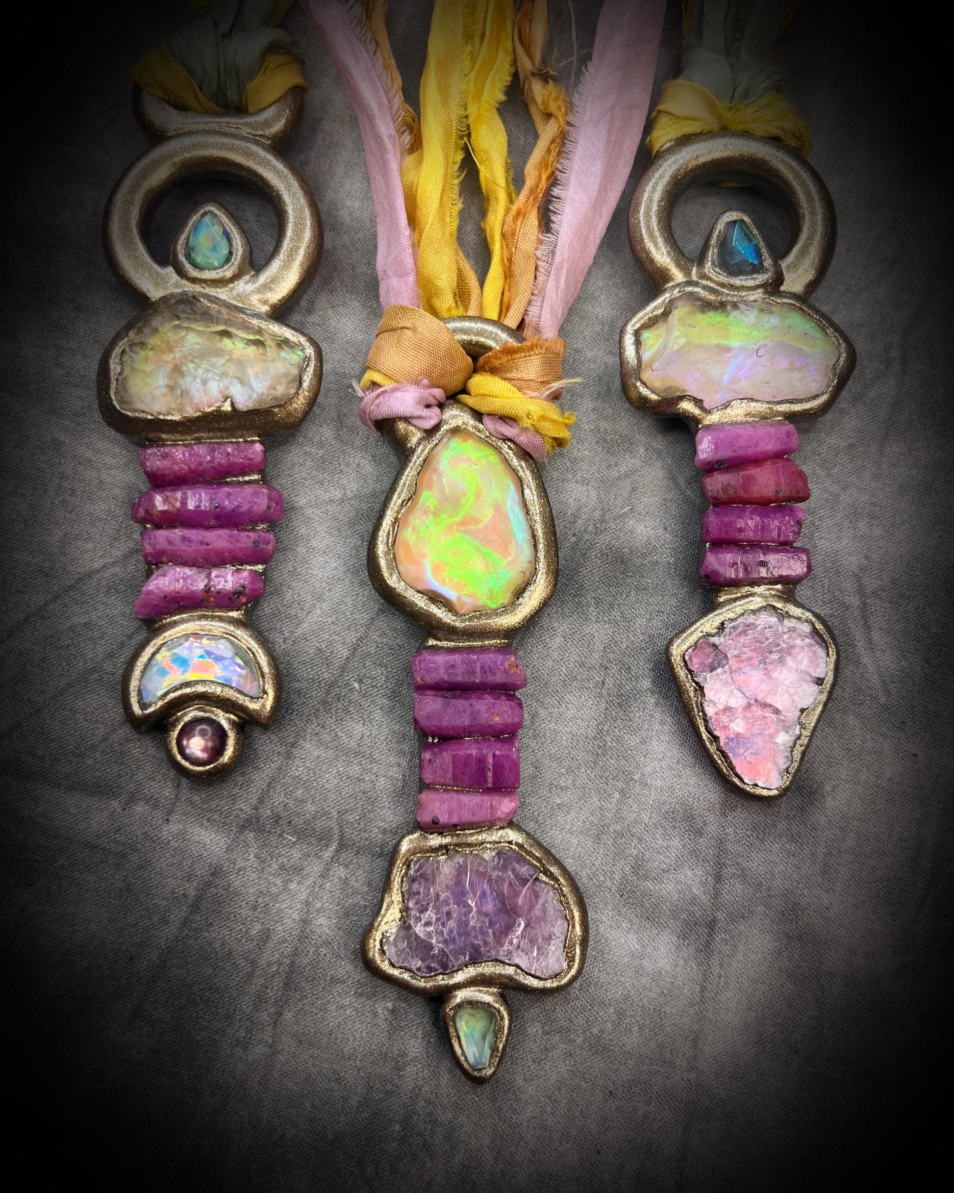 Handmade Libyan Desert Glass talisman necklace with raw ruby crystals, lepidolite, green tourmaline, and recycled silk ties featuring luminous shifting flashes of color.