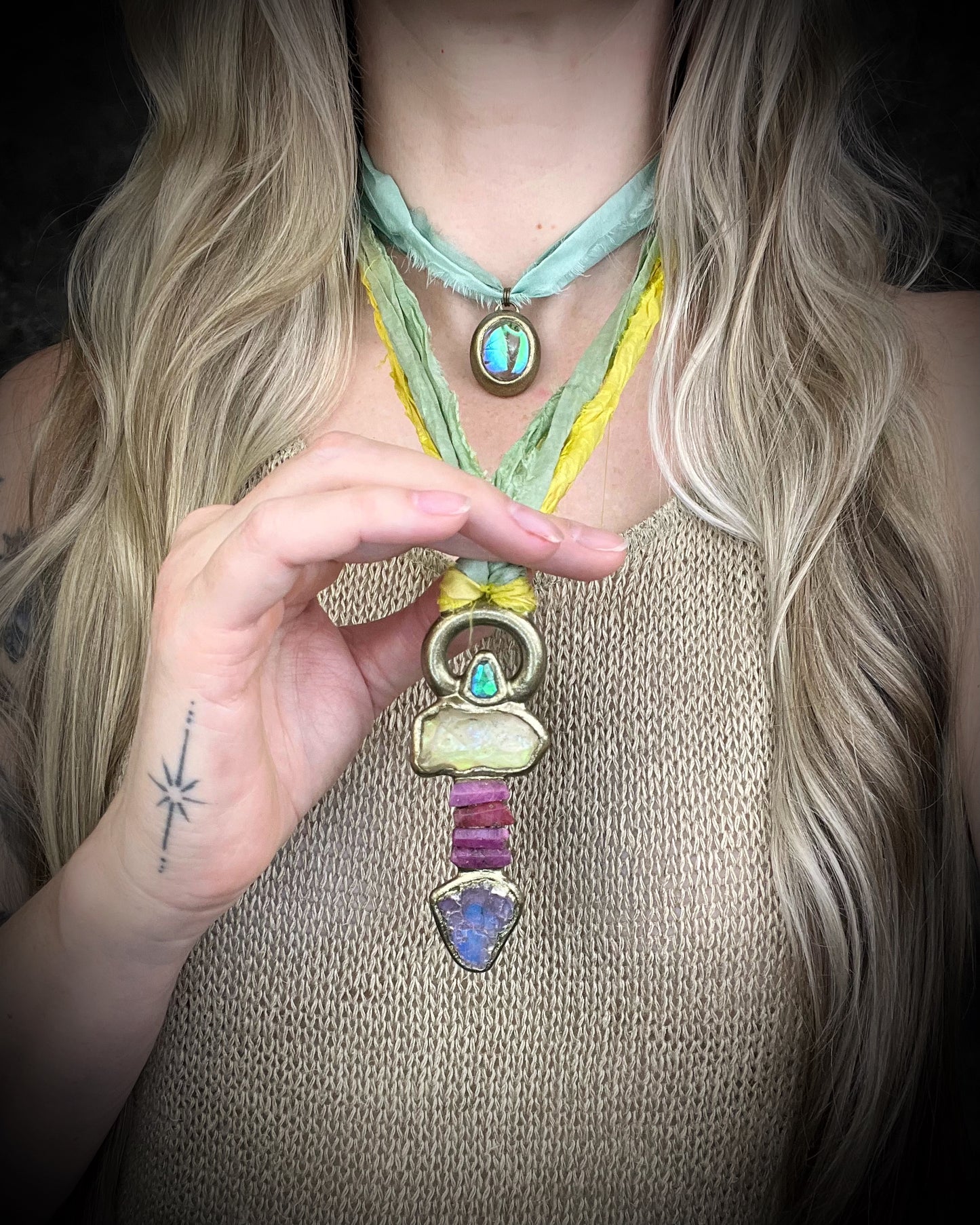 Handmade Libyan Desert Glass talisman necklace with raw ruby crystals, lepidolite, green tourmaline, and recycled silk ties featuring luminous shifting flashes of color.