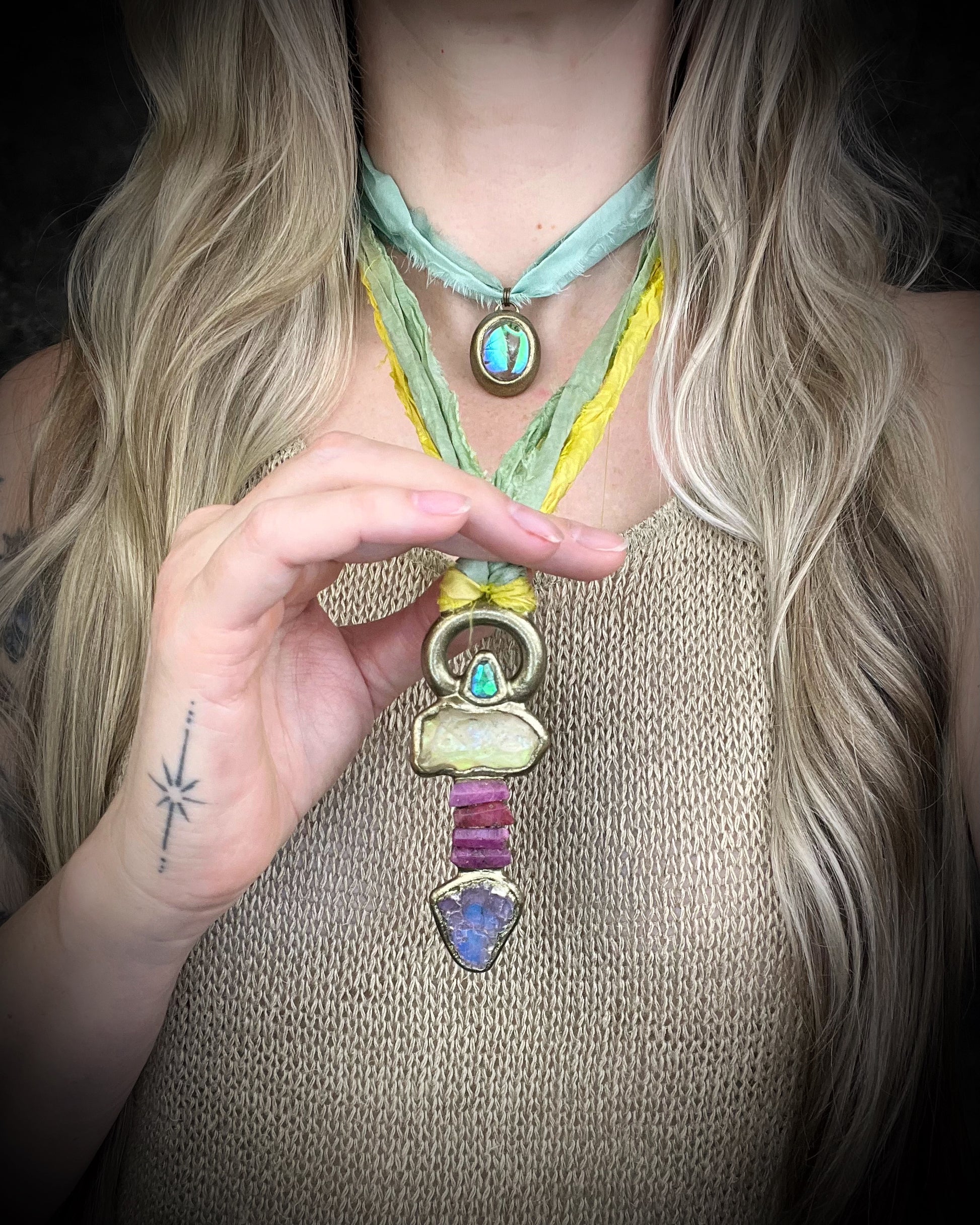 Handmade Libyan Desert Glass talisman necklace with raw ruby crystals, lepidolite, green tourmaline, and recycled silk ties featuring luminous shifting flashes of color.