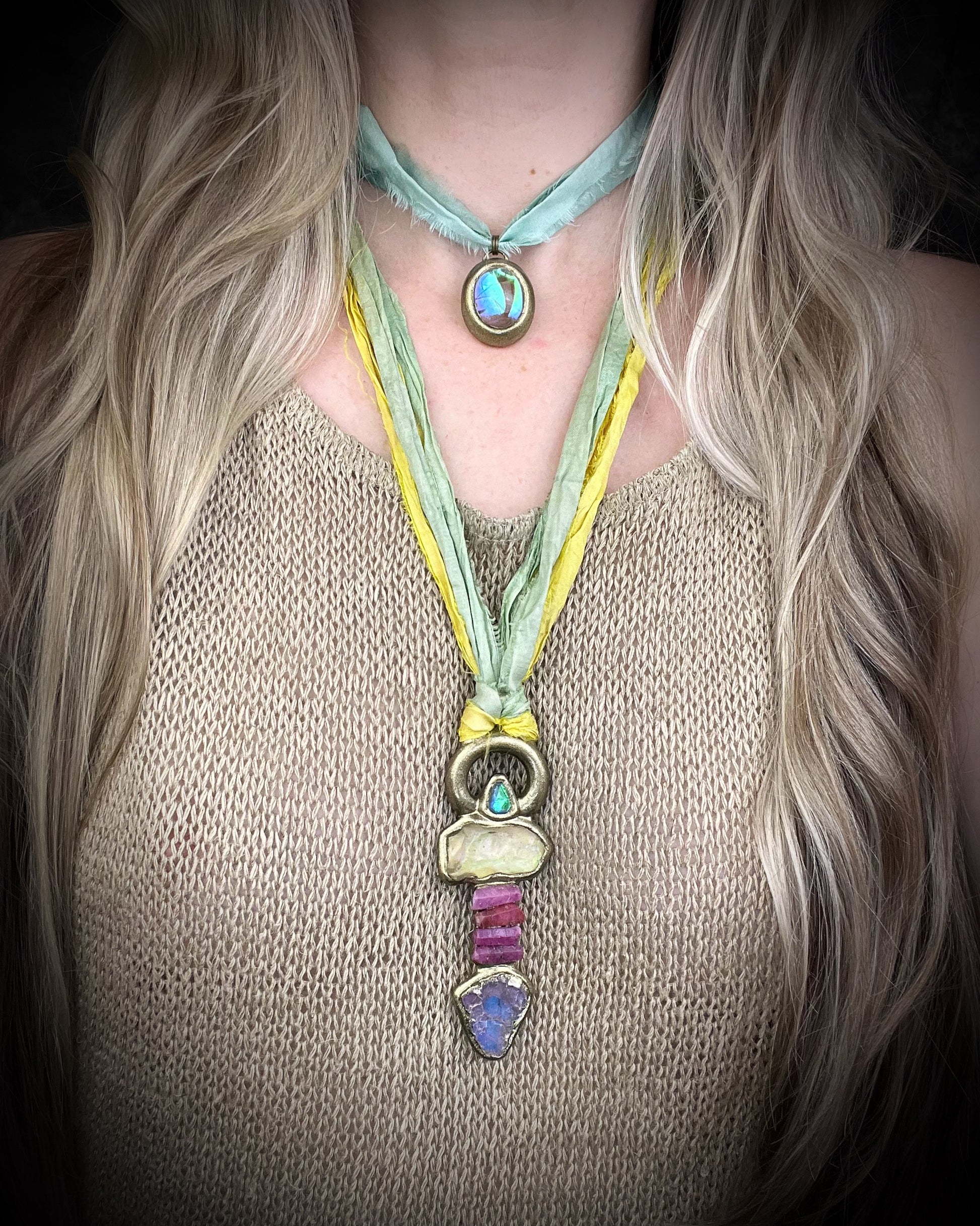 Handmade Libyan Desert Glass talisman necklace with raw ruby crystals, lepidolite, green tourmaline, and recycled silk ties featuring luminous shifting flashes of color.