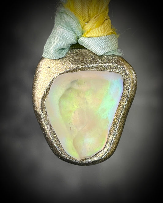 Handmade Libyan Desert Glass talisman with luminous shifting flashes of green, gold, peach, and rose on sea green and yellow recycled silk by Become Spellbound.