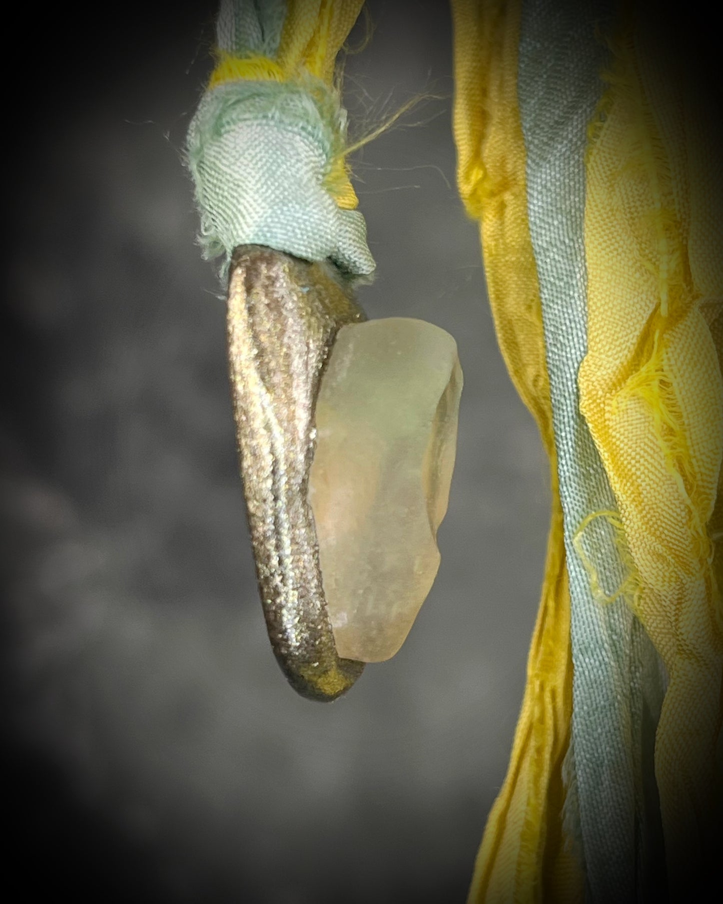 Handmade Libyan Desert Glass talisman with luminous shifting flashes of green, gold, peach, and rose on sea green and yellow recycled silk by Become Spellbound.