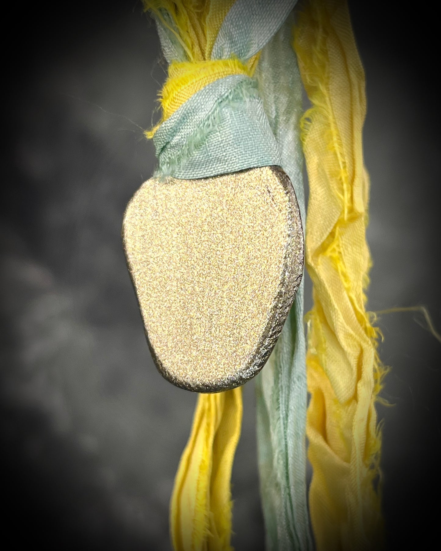 Handmade Libyan Desert Glass talisman with luminous shifting flashes of green, gold, peach, and rose on sea green and yellow recycled silk by Become Spellbound.