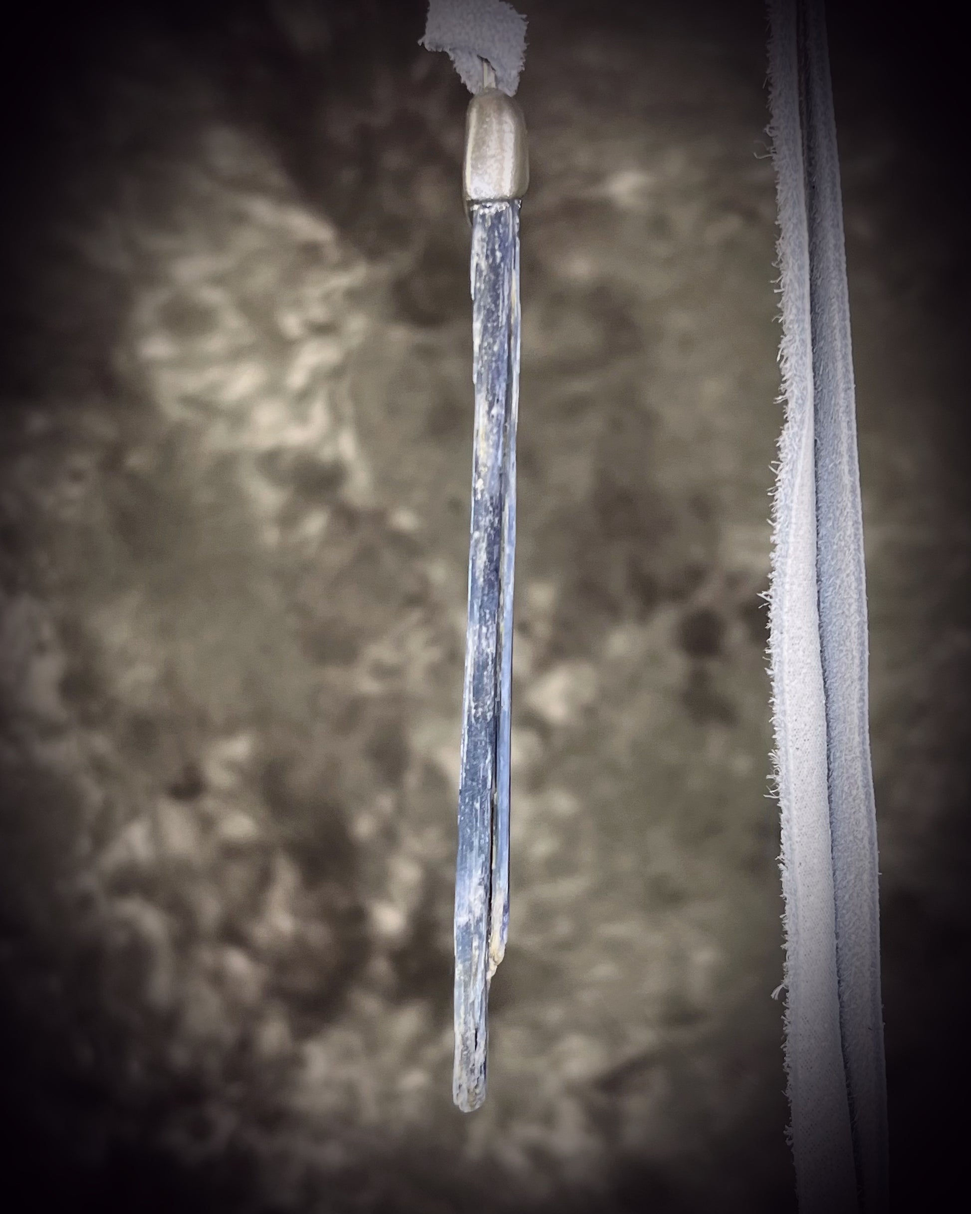 Handmade blue kyanite crystal necklace featuring a natural blue kyanite blade suspended from shimmering silver leather, artisan jewelry by Become Spellbound.