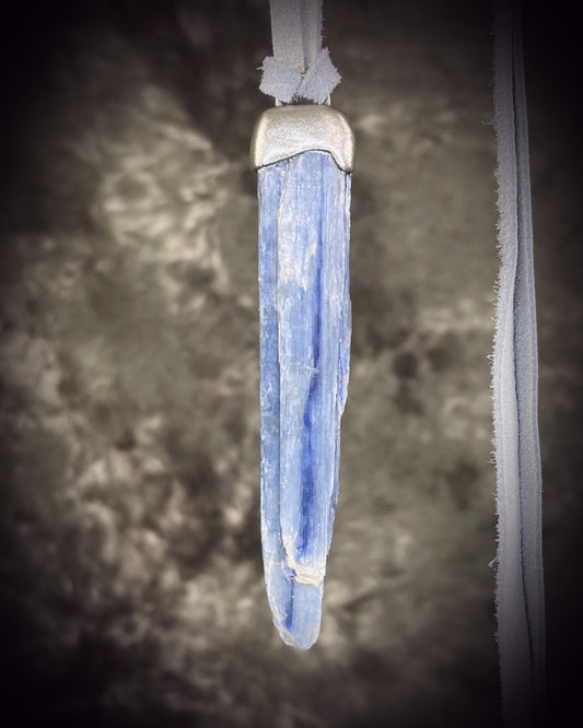 Handmade blue kyanite crystal necklace featuring a natural blue kyanite blade suspended from shimmering silver leather, artisan jewelry by Become Spellbound.