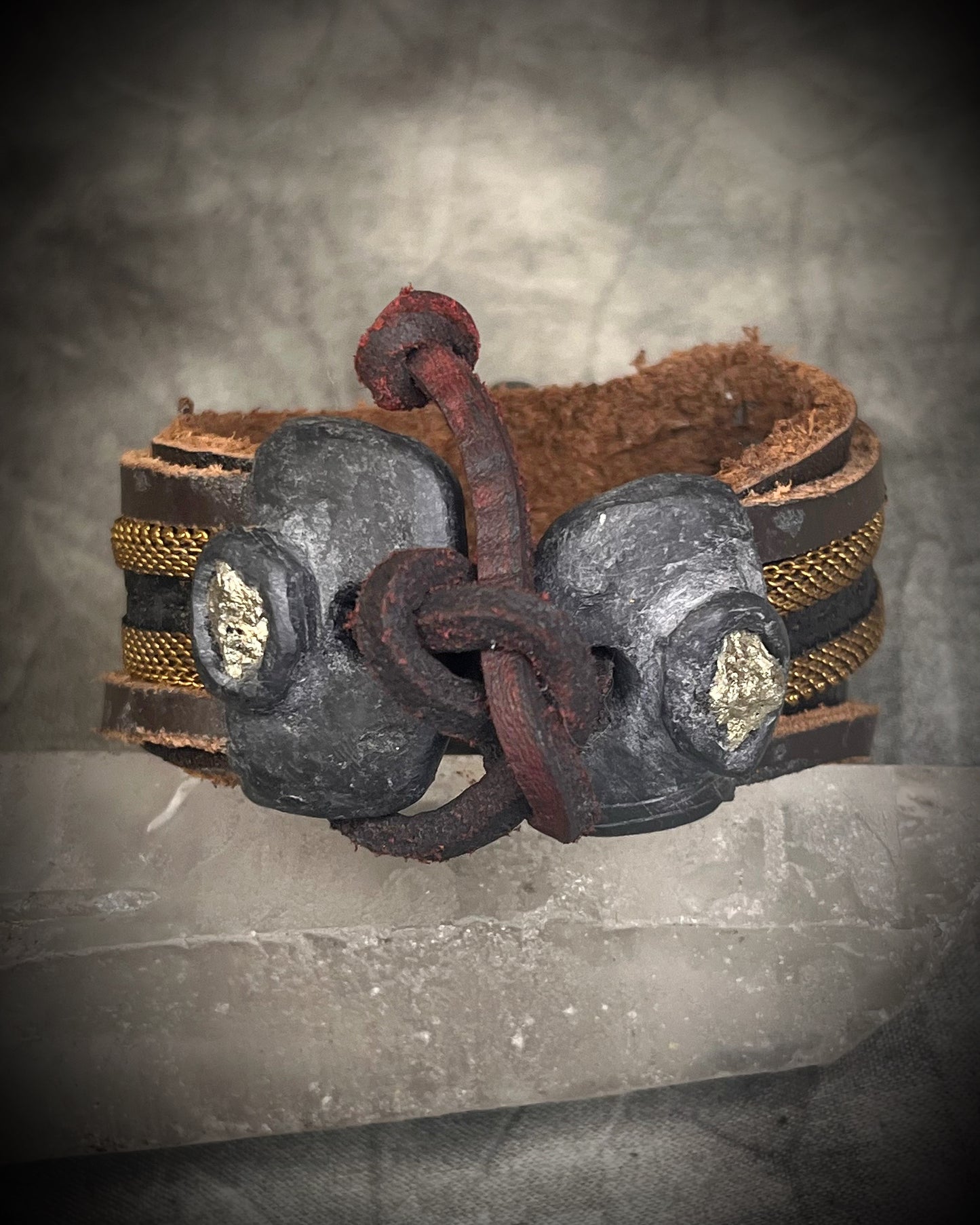 Handmade brown leather cuff bracelet with pyrite focal stone, woven brass chain, pyrite closure details, and adjustable leather tie closure by Anothai Hansen.