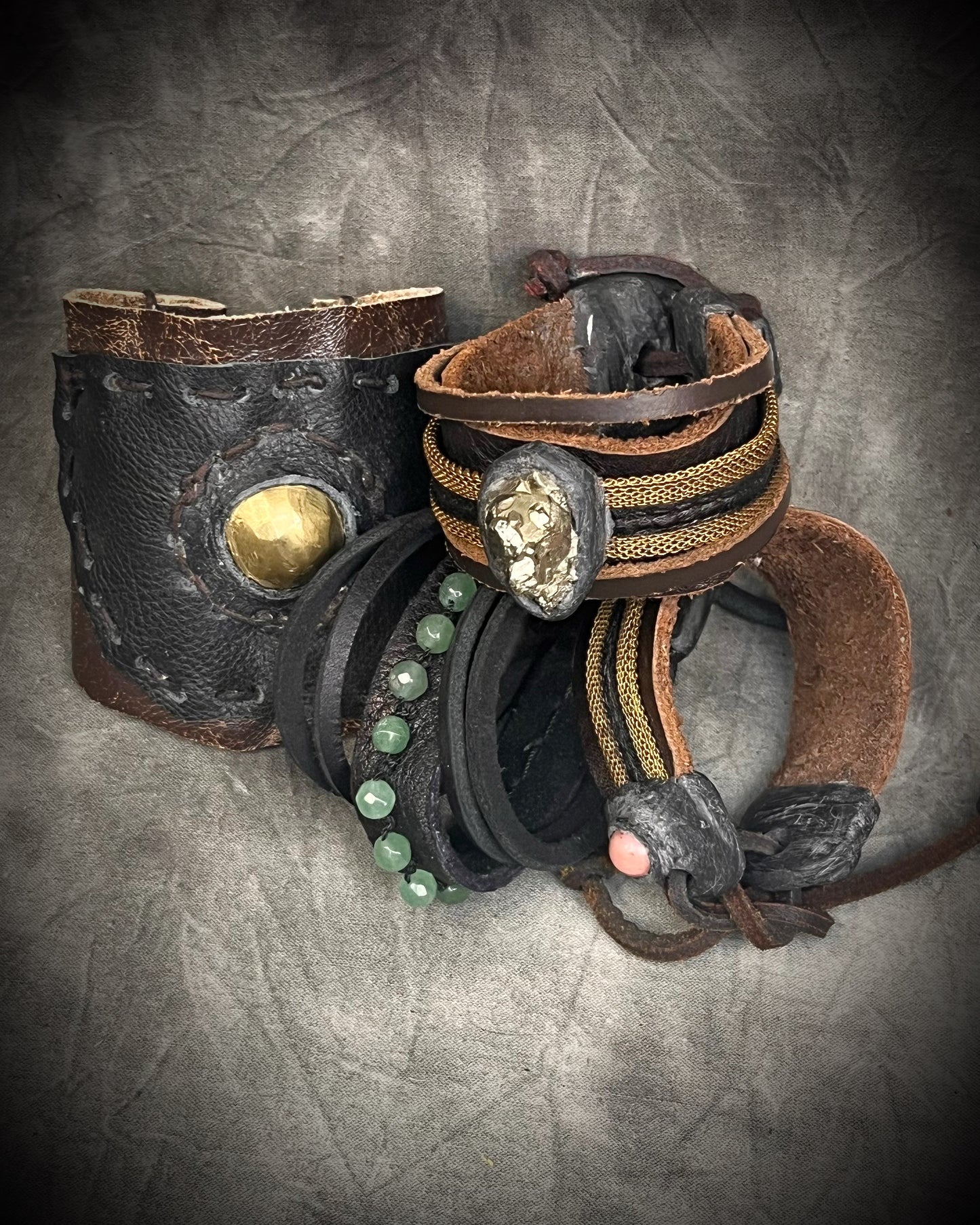 Handmade brown leather cuff bracelet with pyrite focal stone, woven brass chain, pyrite closure details, and adjustable leather tie closure by Anothai Hansen.