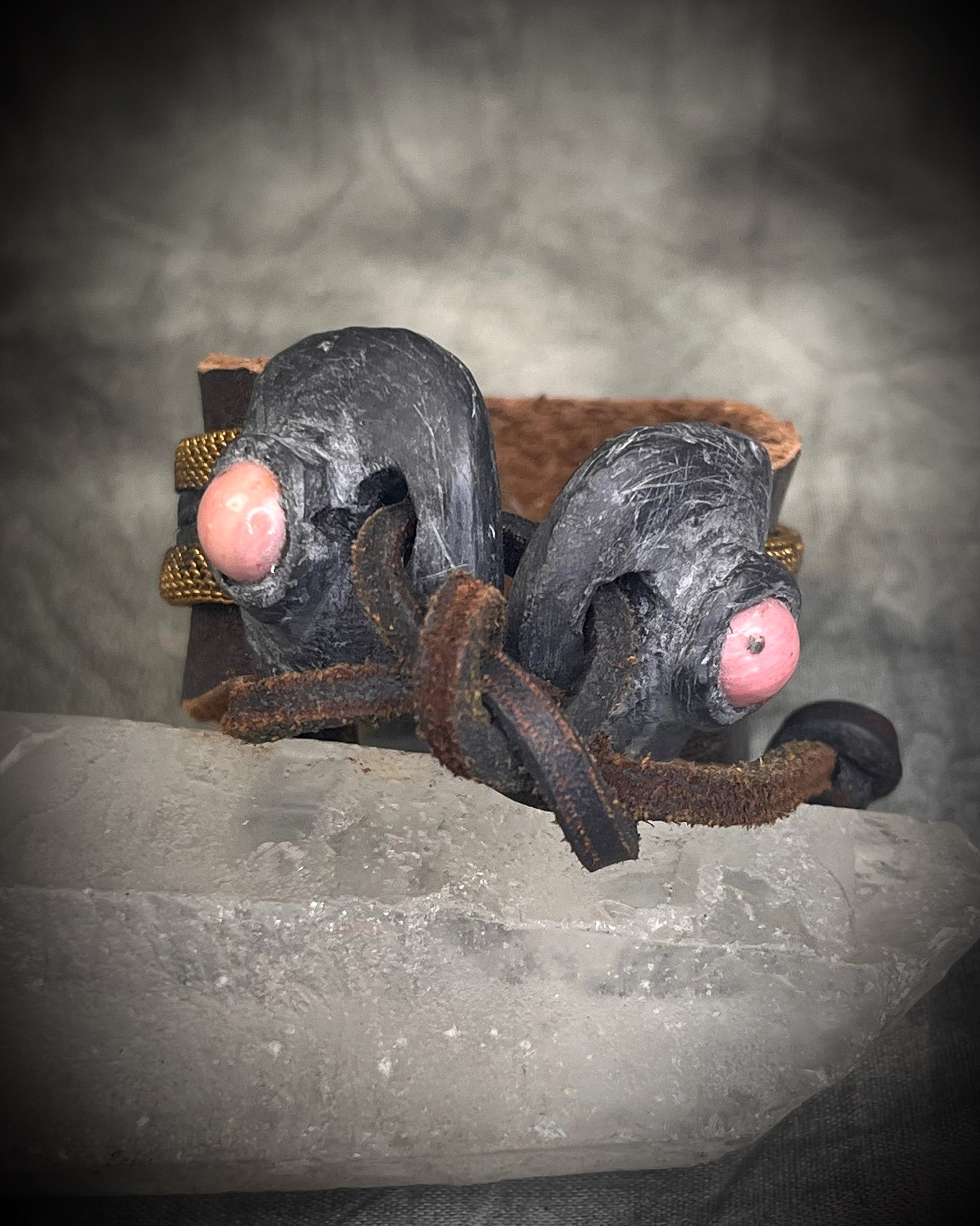 Handmade brown leather cuff bracelet with woven brass chain, rhodonite crystal details, and adjustable leather tie closure by Anothai Hansen.