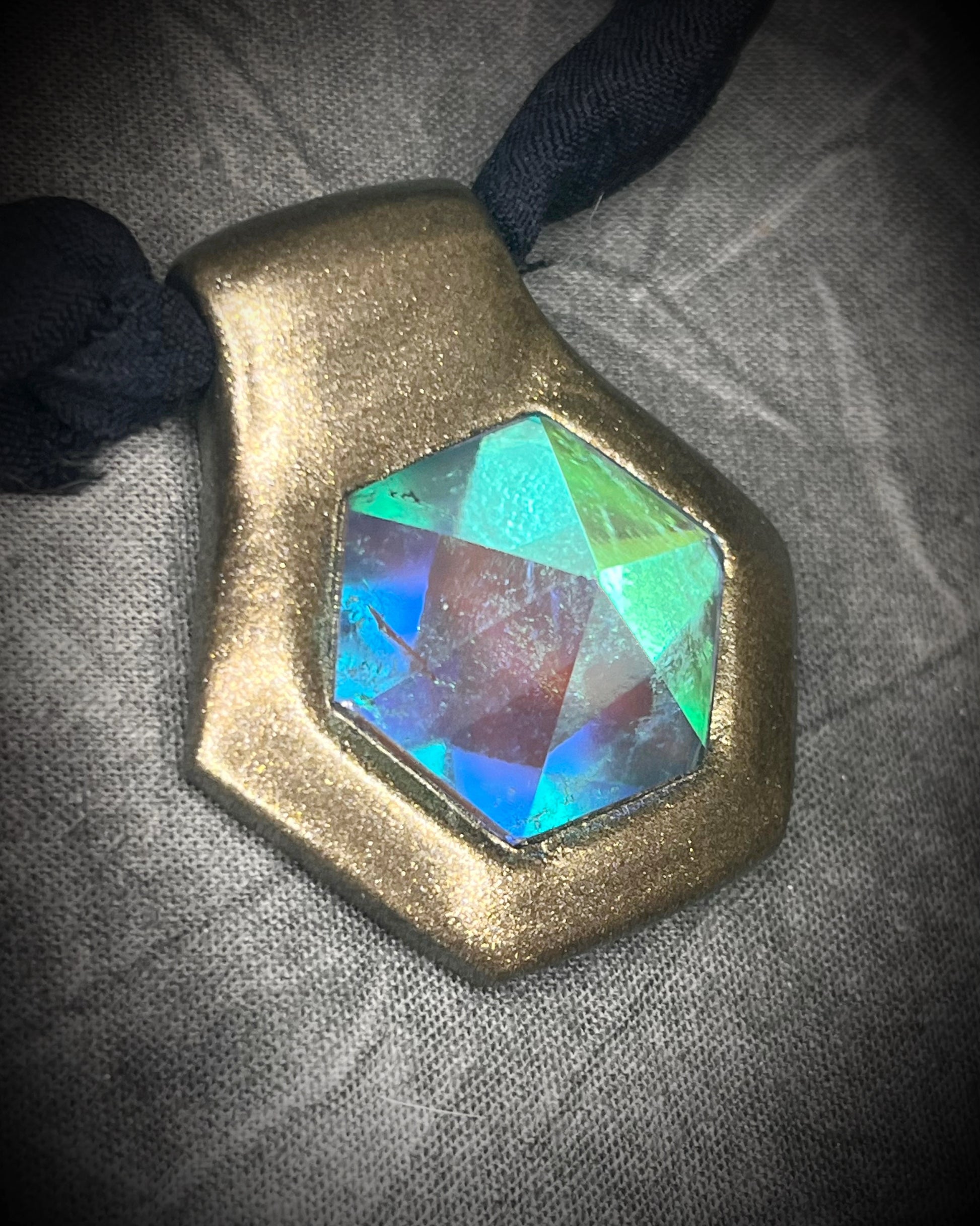 Handmade clear quartz crystal necklace with an aqua flash that feels oceanic and beachy. Framed in gold in a hexagon shape and hung from black recycled silk, this pendant feels like an unearthed treasure. Summer jewelry at its finest!