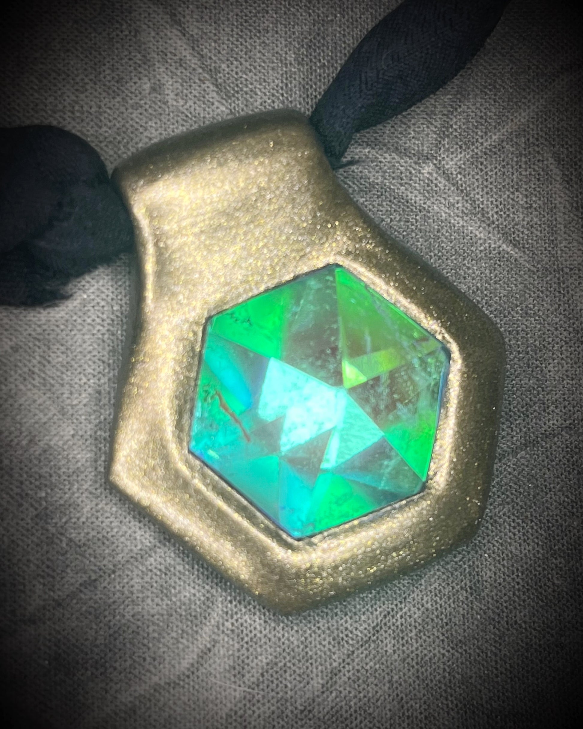 Handmade clear quartz crystal necklace with an aqua flash that feels oceanic and beachy. Framed in gold in a hexagon shape and hung from black recycled silk, this pendant feels like an unearthed treasure. Summer jewelry at its finest!