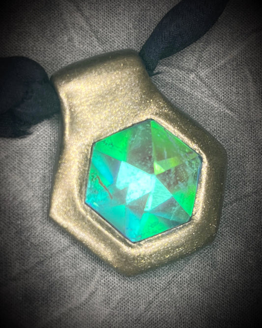 Handmade clear quartz crystal necklace with an aqua flash that feels oceanic and beachy. Framed in gold in a hexagon shape and hung from black recycled silk, this pendant feels like an unearthed treasure. Summer jewelry at its finest!