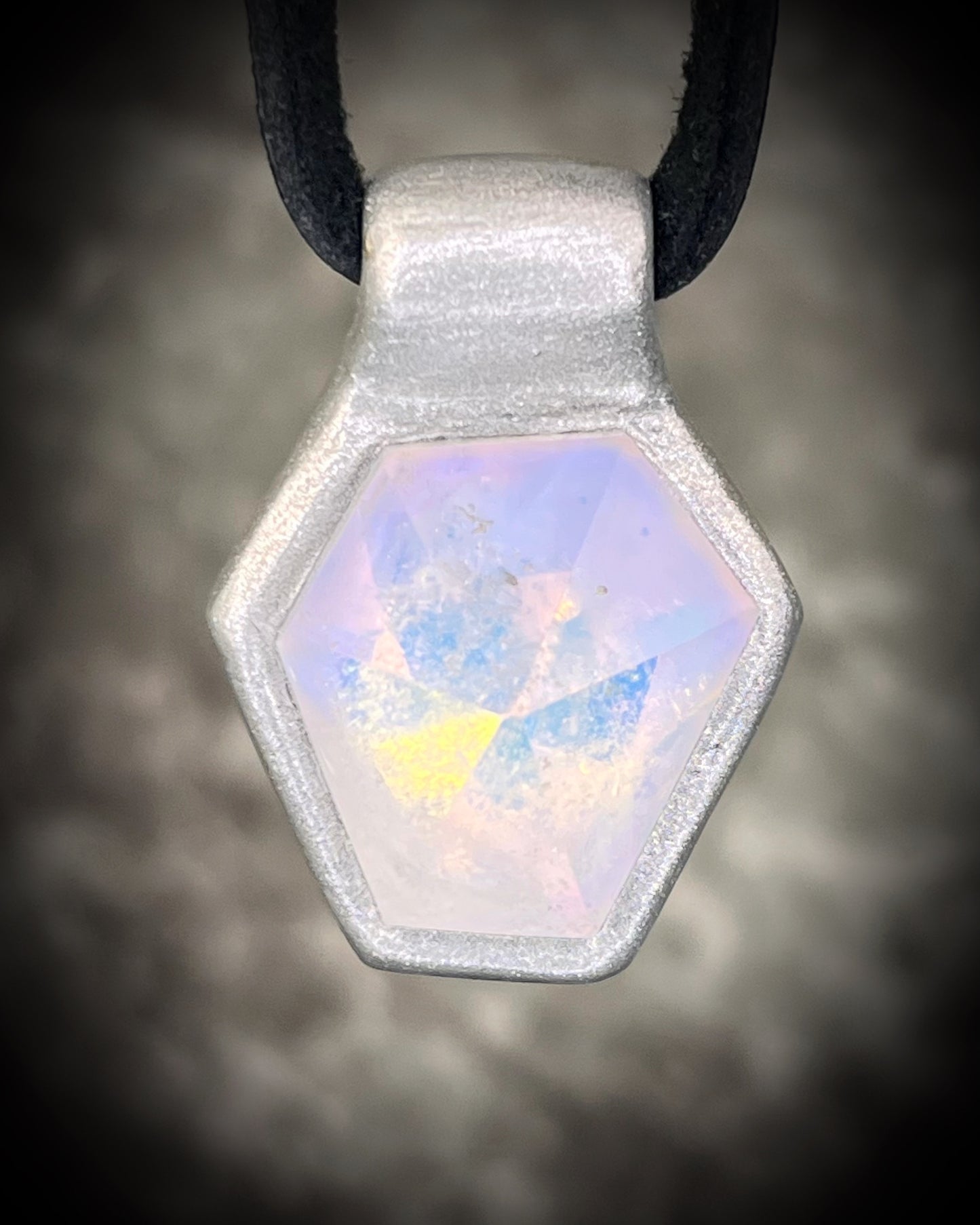 Handmade clear quartz crystal necklace with an opalescent flash that feels enchanted from another realm. Framed in silver in a hexagon shape and hung from black leather, this pendant feels cinematic, and like an unearthed treasure. 