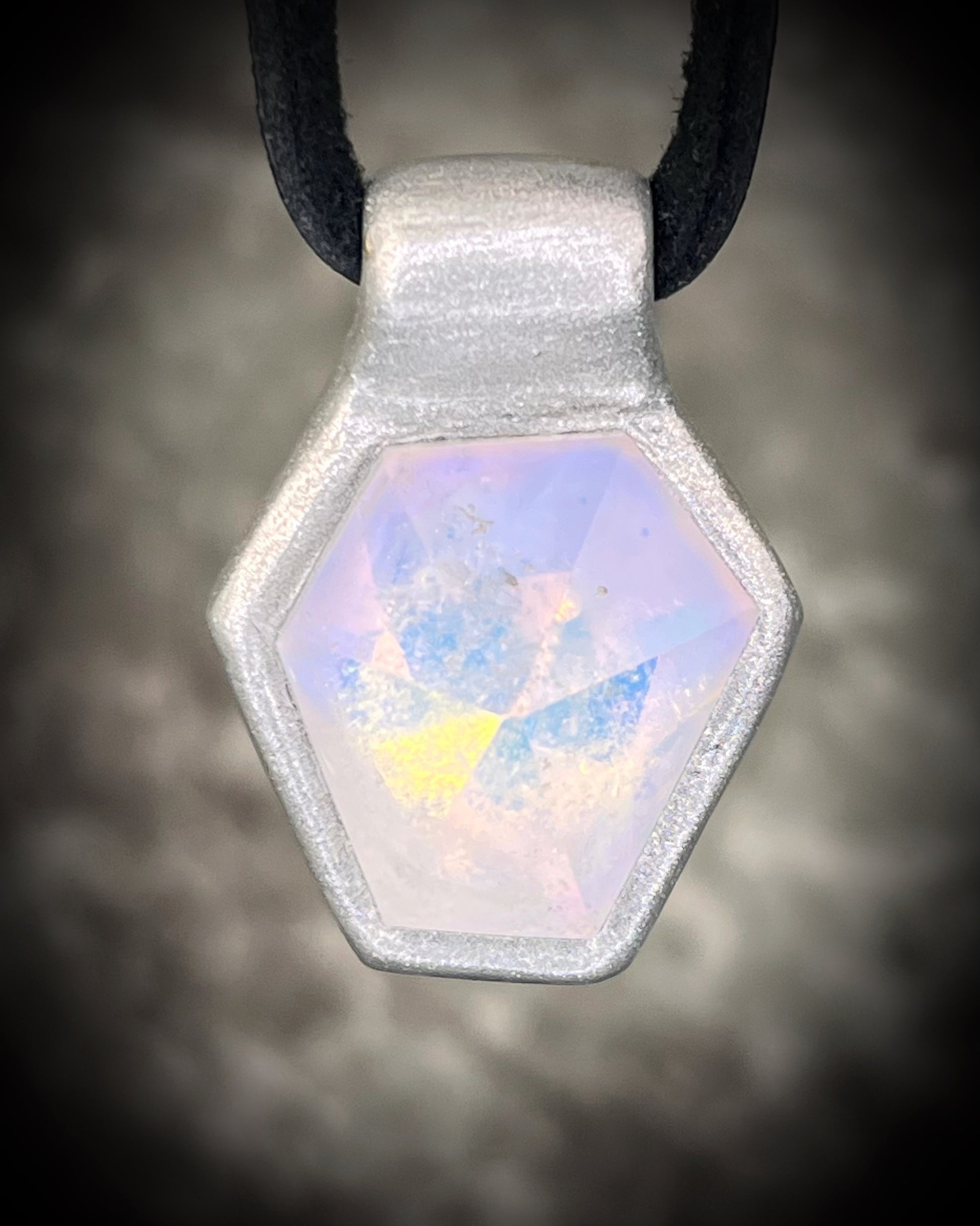 Handmade clear quartz crystal necklace with an opalescent flash that feels enchanted from another realm. Framed in silver in a hexagon shape and hung from black leather, this pendant feels cinematic, and like an unearthed treasure. 