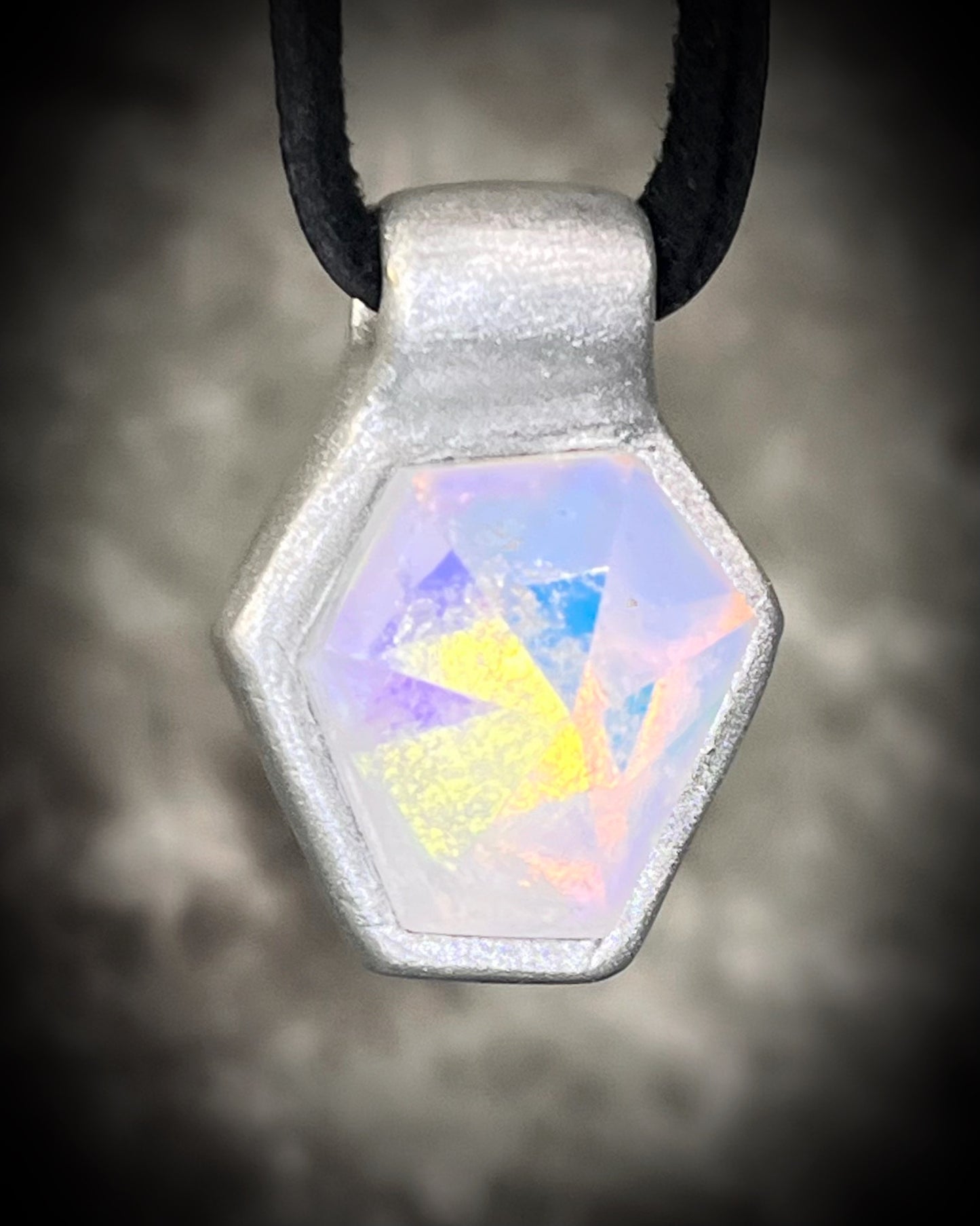 Handmade clear quartz crystal necklace with an opalescent flash that feels enchanted from another realm. Framed in silver in a hexagon shape and hung from black leather, this pendant feels cinematic, and like an unearthed treasure. 