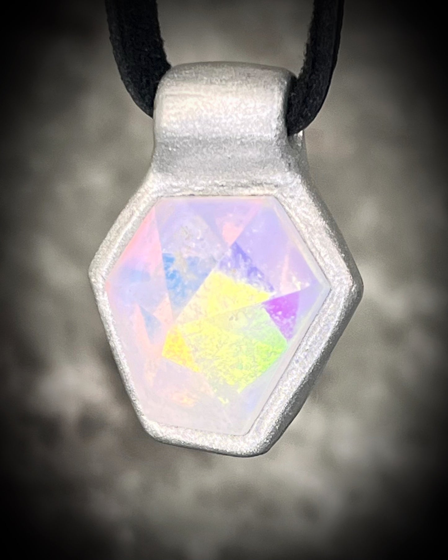 Handmade clear quartz crystal necklace with an opalescent flash that feels enchanted from another realm. Framed in silver in a hexagon shape and hung from black leather, this pendant feels cinematic, and like an unearthed treasure. 