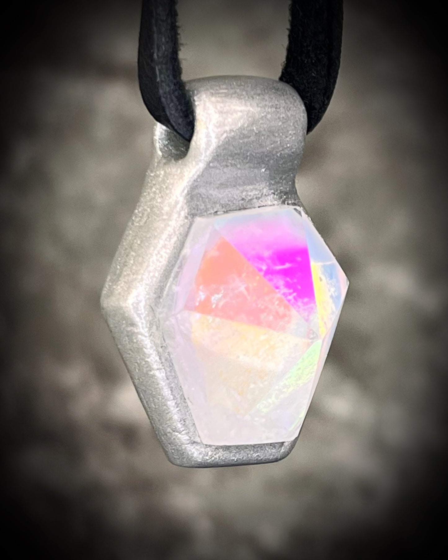 Handmade clear quartz crystal necklace with an opalescent flash that feels enchanted from another realm. Framed in silver in a hexagon shape and hung from black leather, this pendant feels cinematic, and like an unearthed treasure. 
