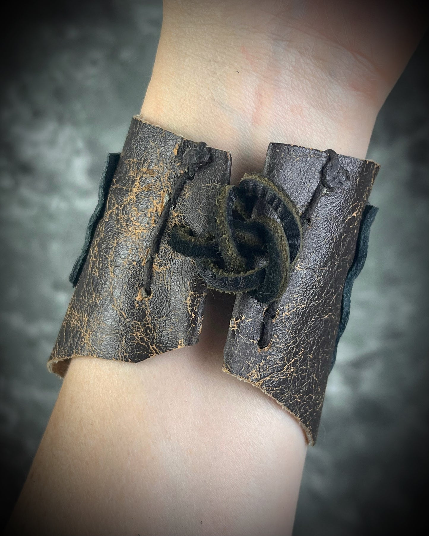 Handmade extra wide 3-inch leather cuff bracelet with layered black and brown leather, brass details, hand stitching, and adjustable leather tie closure by Anothai Hansen.