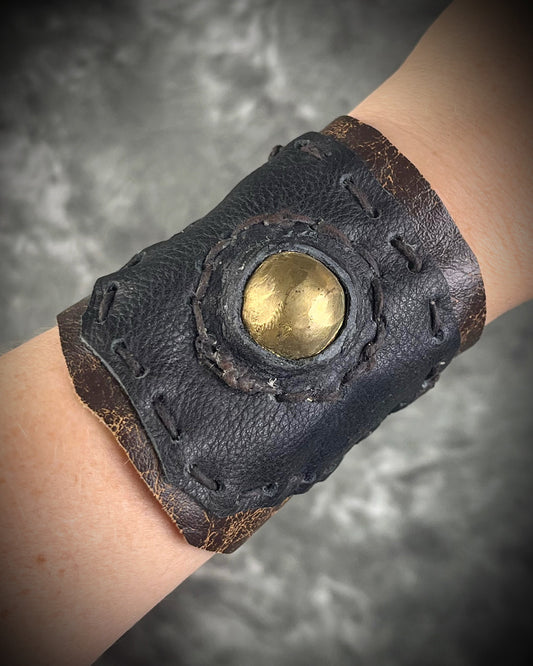 Handmade extra wide 3-inch leather cuff bracelet with layered black and brown leather, brass details, hand stitching, and adjustable leather tie closure by Anothai Hansen.